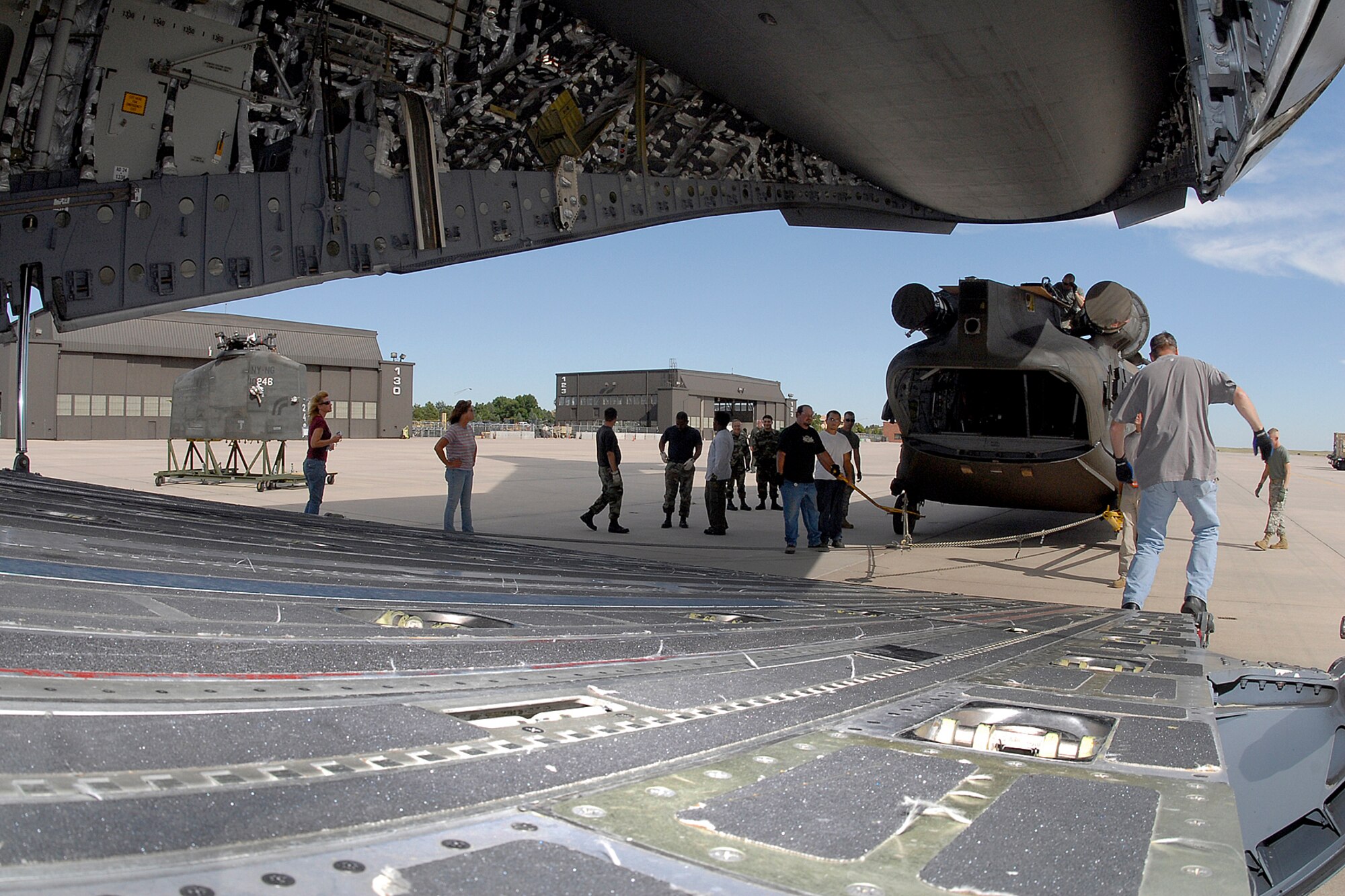 Looking through the maw of a C-17 cargo bay, employees from Sikorsky Support Services Inc., and personnel from Company B, 3rd Battalion, 126th General Support Aviation Battalion, a National Guard unit from New York and Maryland, begin loading a Chinook CH-47D into a C-17 for overseas deployment. (U.S. Air Force photo by Rob Bussard)