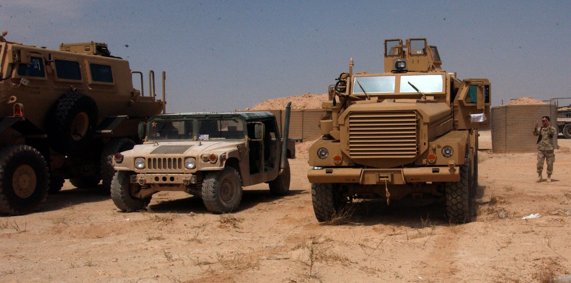 Lt. Col. Gerard Couvillion observes as Tech. Sgt. Shawn Tague backs up a Mine Resistance Ambush Protected vehicle beside a High Mobility Multipurpose Wheeled Vehicle to show the difference between the vehicles Aug. 25 at Al Asad Air Base, Iraq. A MRAP Category III Buffalo model (far left) and MRAP Cougar (far right) will phase out the Humvee. MRAPs are designed to reduce servicemembers' casualties by protecting them from improvised explosive devices, increase their mobility and enhance mission success throughout the areas of responsibility. Sergeant Tague is assigned to the 438th Aerial Port Flight and is deployed from Pope Air Force Base, N.C. Colonel Couvillion is the 438th Expeditionary Support Squadron commander. (U.S. Air Force photo/Senior Airman Olufemi A. Owolabi) 
