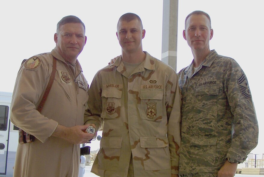 ALI AIR BASE, IRAQ -- Senior Airman Jere Wheeler, deployed 7th Civil Engineer Squadron firefighter, receives a coin from Lt. Gen. Gary North, 9th Air Force and U.S. Central Command Air Forces commander, Aug. 22. The soon-to-be staff sergeant was recognized for his response to some outside the wire vehicle accidents with the 407th Rescue Air Mobility Squadron. (Photo courtesy of Master Sgt. Timothy Brown)