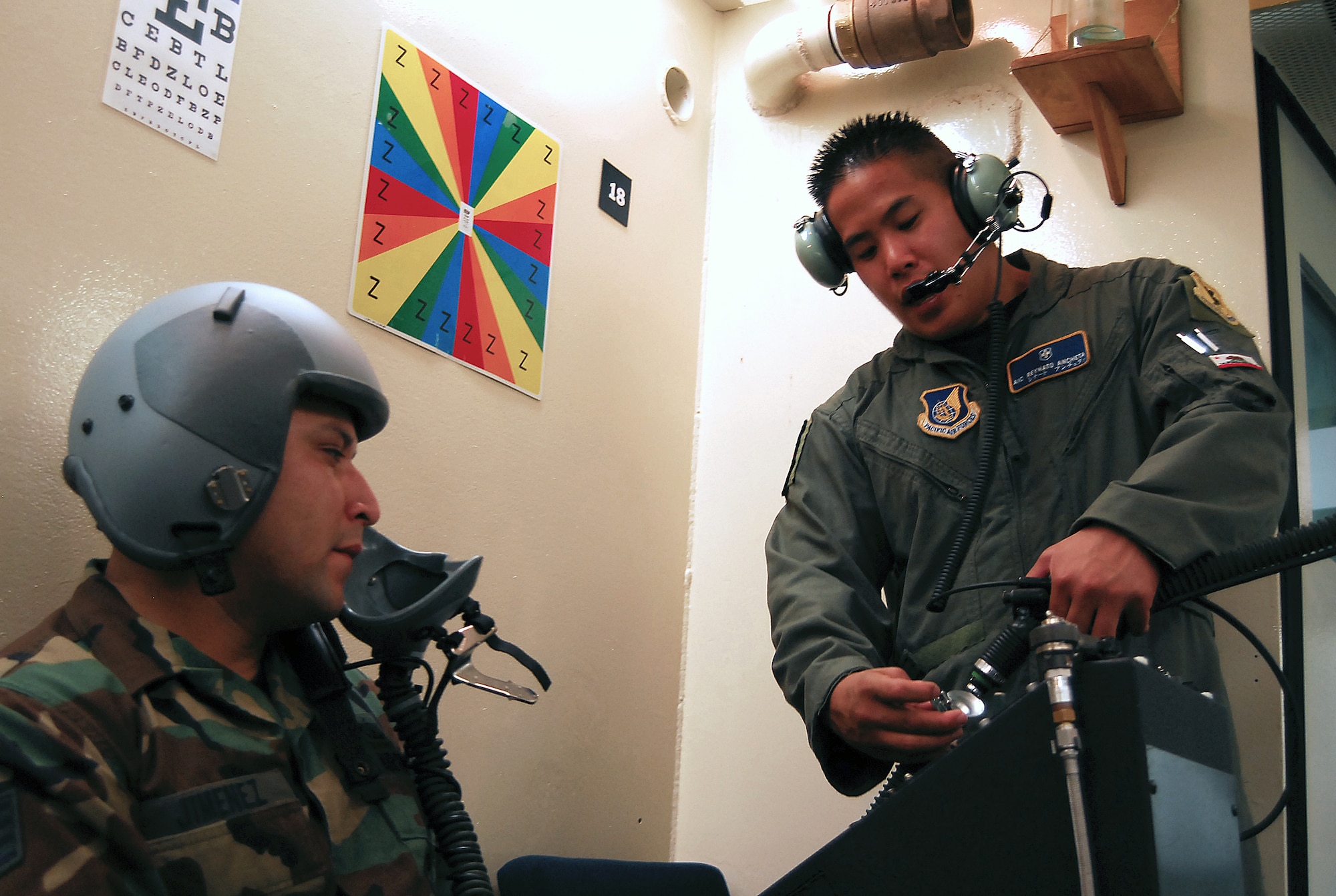 Airman 1st Class Reynato Ancheta demonstrates to Staff Sgt. Pedro Jimenez how to connect the mask breathing unit into the altitude chamber's oxygen supply Aug. 28, 2007, Kadena Air Base, Japan.  The mission of the altitude chamber is to teach military personnel who fly in aircraft, to identify, recognize and treat symptoms of hypoxia.  Airman Ancheta is an instructor for the Physiological Training Flight, 18th Aerospace Medicine Squadron.  Sergeant Jimenez is assigned to 36th Wing Public Affairs .  U.S. Air Force photo/Airman 1st Class Kelly Timney
