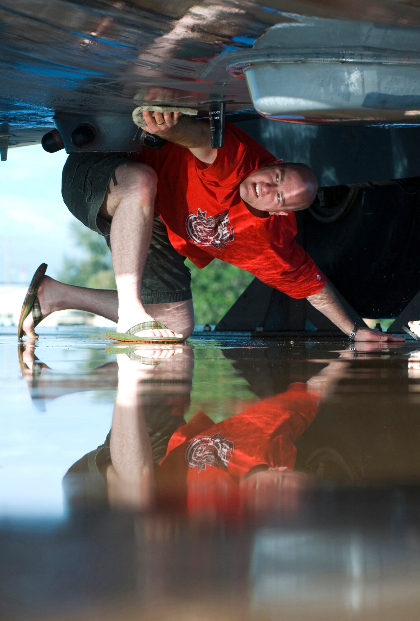 ELMENDORF AIR FORCE BASE, Alaska - Reflections from a pool of water casts light on Senior Airman George McVey, 3rd Medical Support Squadron, as he scrubs the underbelly of the C-130 Hercules during a biannual static wash Aug. 30. More than 70 volunteers from 15 squadrons participated in the Fall Wash. The static displays must be washed twice a year according to an Air Force instruction. (U.S. Air Force photo by Senior Airman Garrett Hothan)