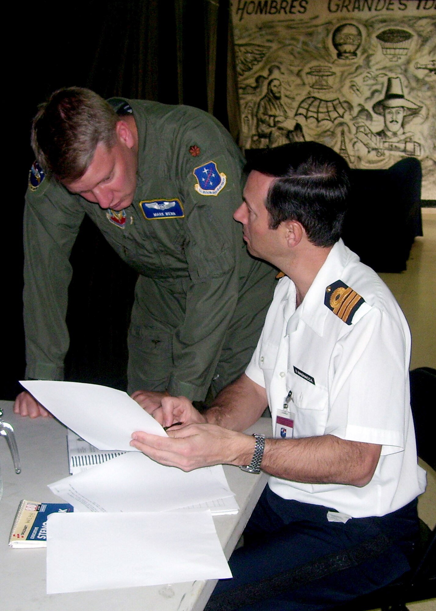 Argentinean Cmdr. Fabian Magnacca and Maj. Mark Webb discuss last minute flight communication details at Tocumen International Airport in Panama during PANAMAX 2007 Sept. 1. Civil and military forces from 19 countries will participate in PANAMAX, a U.S. Southern Command joint and multi-national training exercise co-sponsored with the Government of Panama, in the waters off the coasts of Panama and Honduras. Major Webb is assigned to the Combined Forces Air Combatant Command. (U.S. Navy photo/Lt. Cmdr. Bill Anderson)
