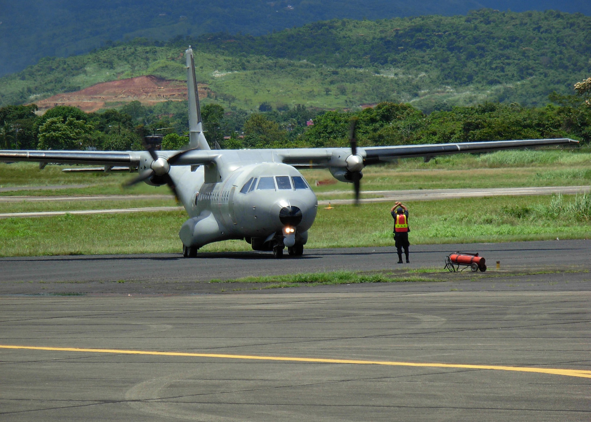 A Panamanian airman guides a Colombian aircraft onto the tarmac at Tocumen International Airport in Panama during PANAMAX 2007 Sept. 1. Civil and military forces from 19 countries are participating in the U.S. Southern Command joint and multi-national training exercise co-sponsored with the Government of Panama, in the waters off the coasts of Panama and Honduras. (U.S. Navy photo/Petty Officer 2nd Class Lolita Lewis)
