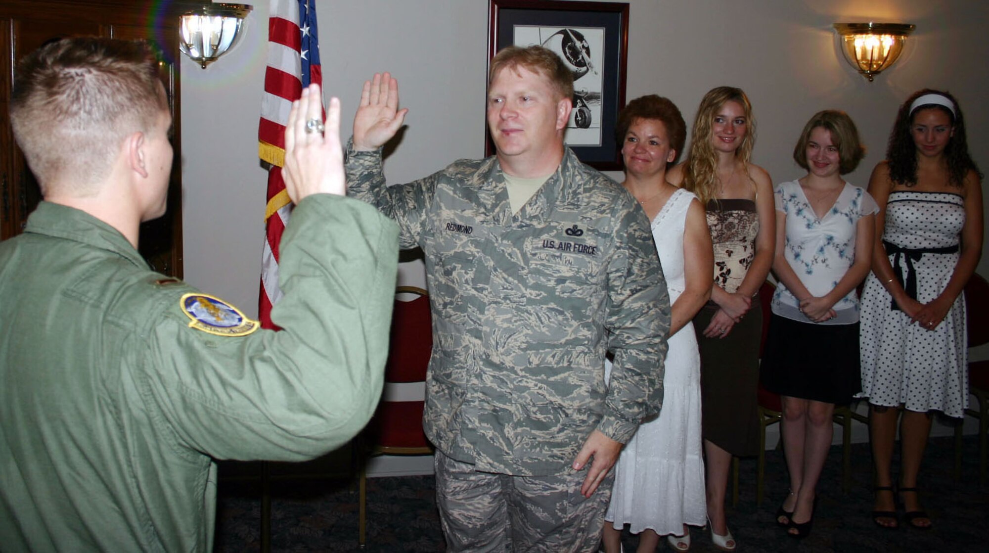 LAUGHLIN AIR FORCE BASE, Texas -- Chief Master Sgt. Chris Redmond, command chief for Air Force Office of Special Investigations, raises his hand and repeats after swear his oldest son, 24-year-old 2nd Lt. Chris Redmond the 85th Flying Training Squadron, while family watches recently. 