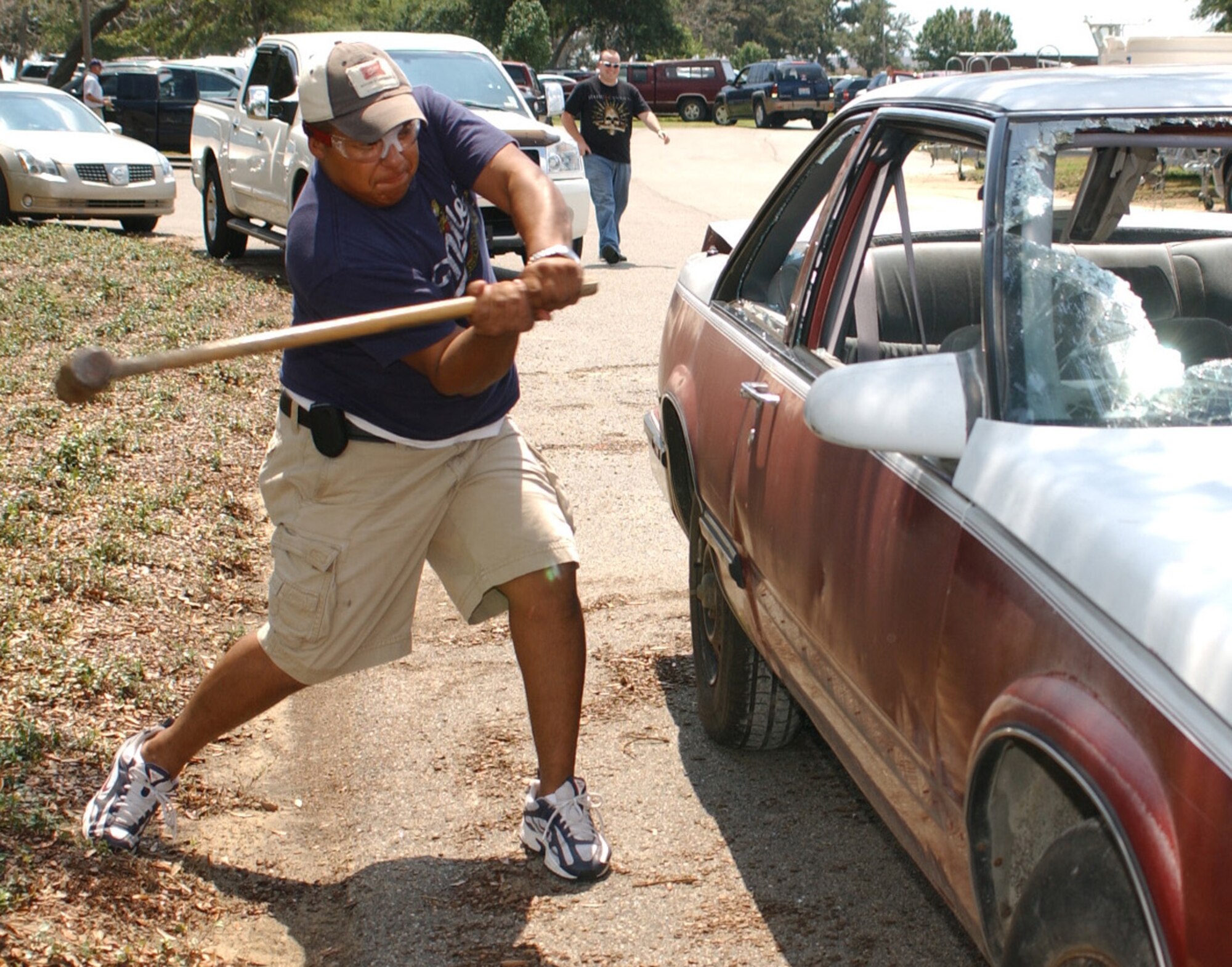 Senior Airman George Olivo, 81st Civil Engineer Squadron, takes a whack at a wrecked car, a stress-relief device at the picnic.  (U.S. Air Force photo by Kemberly Groue)