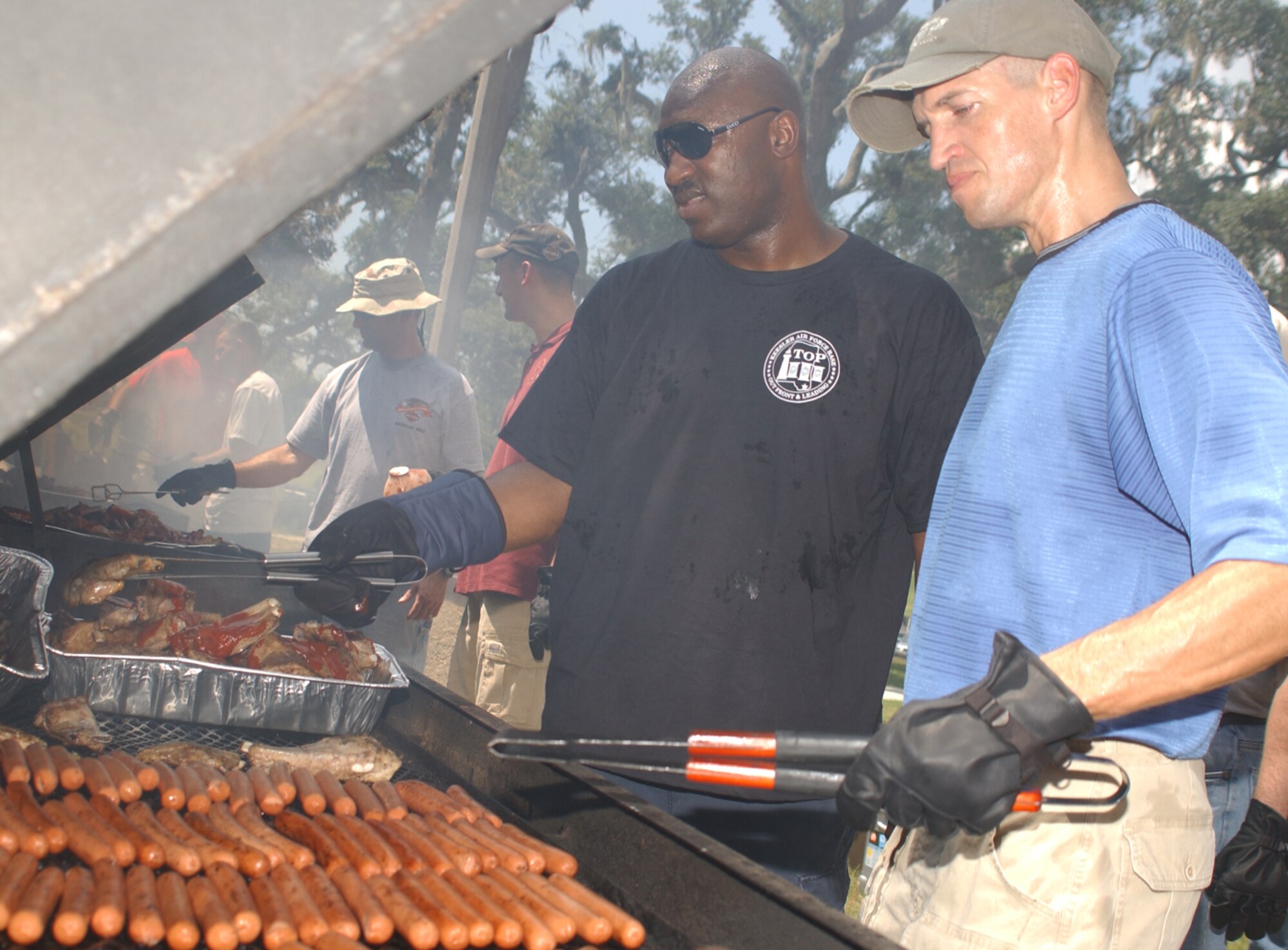 Senior Master Sgt. Stuart Hedgeman, left, 81st Communications Squadron, and Chaplain (Capt.) Jeremy Gorline grill hot dogs and ribs at the picnic.  Sergeant Hedgeman is a member of Top III and Chaplain Gorline belongs to the company grade officers council which volunteered to help with food preparation.  Corporate sponsors included Abita Springs, Allegiant Air, Barry’s U-Pull-It Auto Parts, Coca-Cola, D’Iberville Equipment Rental and Sales, Gulf Islands Water Park, Kim Beck Kia, MILES, Mississippi Sea Wolves, New Orleans Saints, Sea World Orlando, University of Southern Mississippi Golden Eagles and Universal Studios Orlando.   (U.S. Air Force photo by Kemberly Groue)