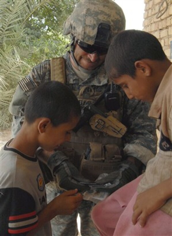A U.S. Army soldier from Echo Company, 96th Civil Affairs Battalion shows pictures of his children to Iraqi children on Aug. 1, 2007.  Echo Company is attached to the 4th Stryker Brigade Combat Team, 2nd Infantry Division.  
