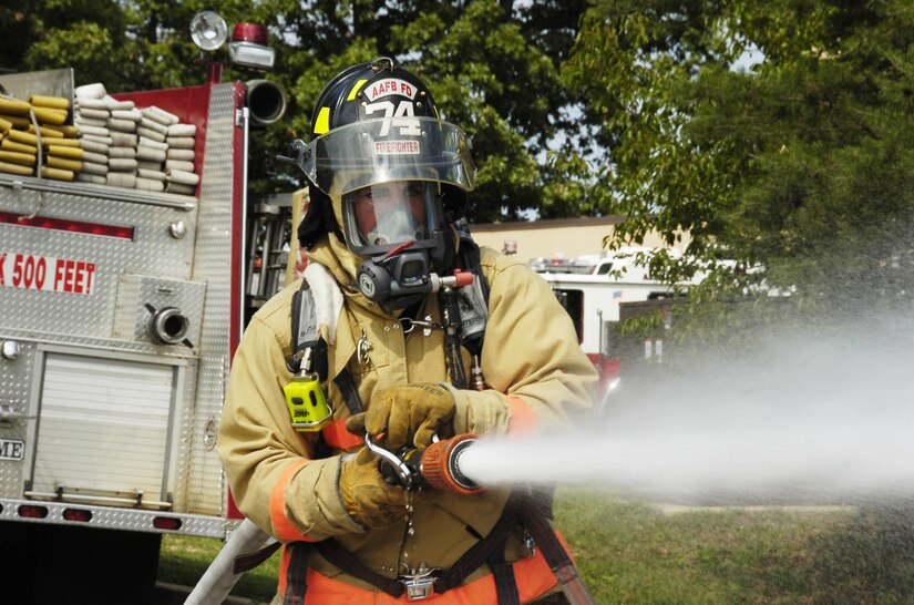 Airman Tim Mulvaney discharges a fire hose to knock down a cone during the Firefighters Confidence Course.