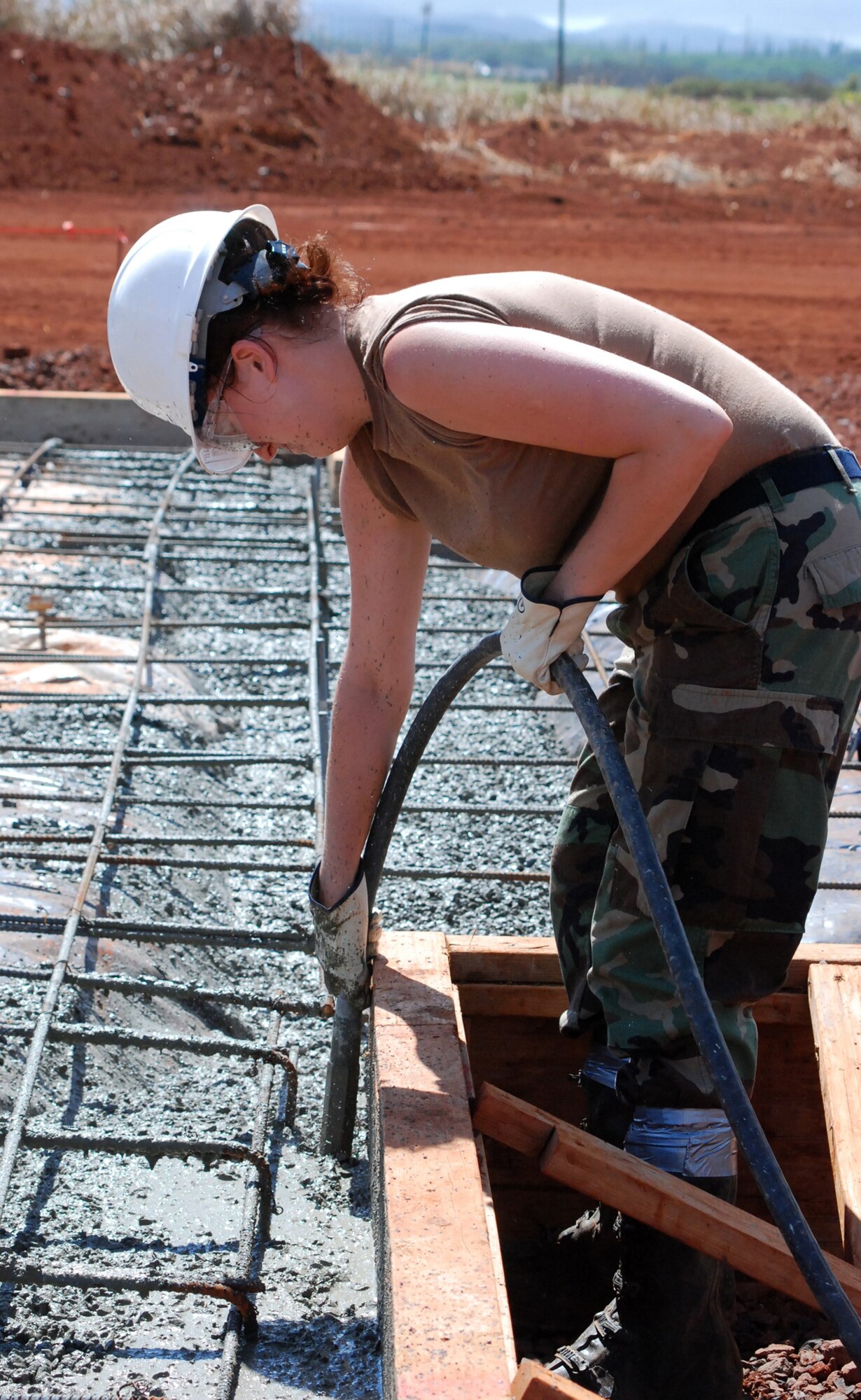 Airman 1st Class Lisa Smith, 301st Civil Engineer Squadron Naval Air Station Joint Reserve Base Fort Worth, Texas, administration apprentice operates a concrete vibrater to consolidate the concrete around the reinforcing steel. The 36-member team worked on this Innovative Readiness Training project at the Helemano Plantation in Oahu, Hawaii., for two weeks performing concrete foundation construction; framing; commercial/residential electrical work; entomology; supply; and surveying to name a few areas. 