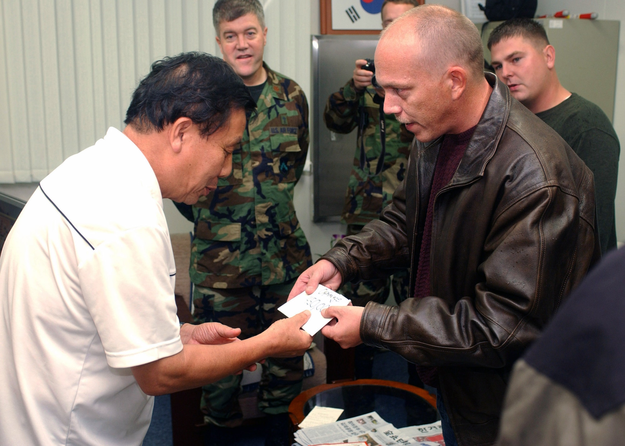 Master Sgt. William Highlander presents 450,000 Won (approximately $500) to David Kim at the Gunsan Orphanage Sept. 5 at Gunsan City, South Korea. Sergeant Highlander and 12 other Airmen from the 8th Logistics Readiness Squadron volunteered at the Kunsan Air Base Commissary in South Korea to raise money for the children at the Gunsan Orphanage as part of a Good Neighbor Program initiative. Sergeant Highlander is the 8th Logistics Readiness Squadron Distribution NCO in charge. (U.S. Air Force photo/Senior Airman Steven R. Doty) 
