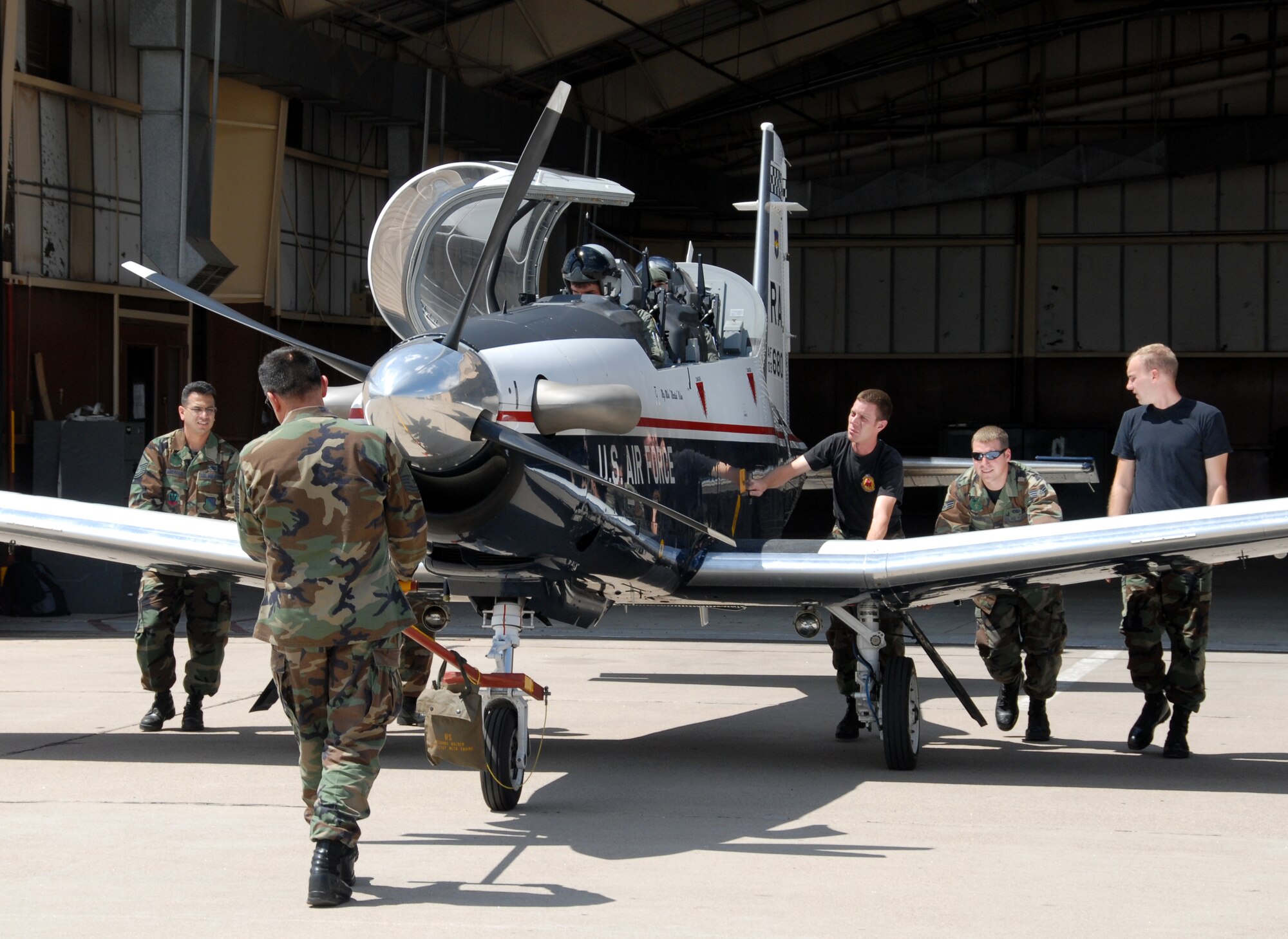 CANNON AIR FORCE BASE, N.M. -- Airmen from the 27th Equipment Maintenance Squadron push a T-6A Texan II primary trainer from a hangar at Cannon Air Force Base, N.M.  The Airmen are, left to right, Master Sgts. Victor Andrade and Silvestre Barajas, Staff Sgt. Eric Peaslee, and Senior Airmen Timothy Dunning and Matthew Palesky.  Inside the aircraft are Maj. Tommy Hudnall, an instructor pilot with the 12th Flying Training Wing, Randolph Air Force Base, Texas, and Lt. Col. Ancel Yarbrough, the 27th Fighter Wing Chief of Safety at Cannon. Two Texan IIs and their pilots visited Cannon AFB on Aug. 23-24 to demonstrate the capabilities of the T-6 and drum up interest among 27th FW F-16 pilots to become instructor pilots.  (Air Force photo by Chief Master Sgt. Gary Emery)