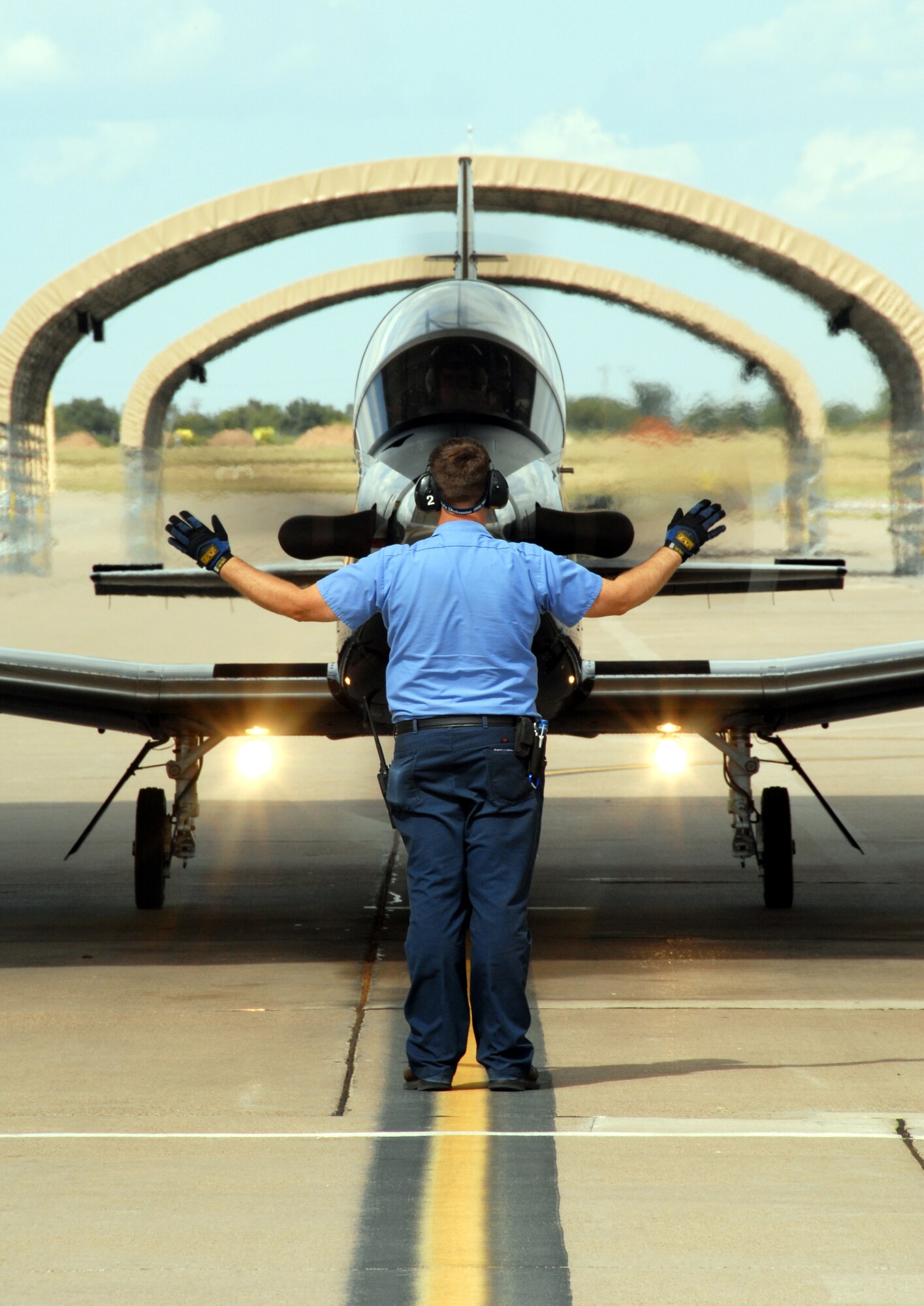 CANNON AIR FORCE BASE, N.M. -- Robert Taggart, an aircraft servicer with the transient alert section at Cannon Air Force Base, N.M. guides a T-6A Texan II primary trainer to its parking spot after a flight.  Two Texan IIs and their pilots visited Cannon AFB on Aug. 23-24 to demonstrate the capabilities of the T-6 and drum up interest among 27th FW F-16 pilots to become instructor pilots.  (Air Force photo by Chief Master Sgt. Gary Emery)