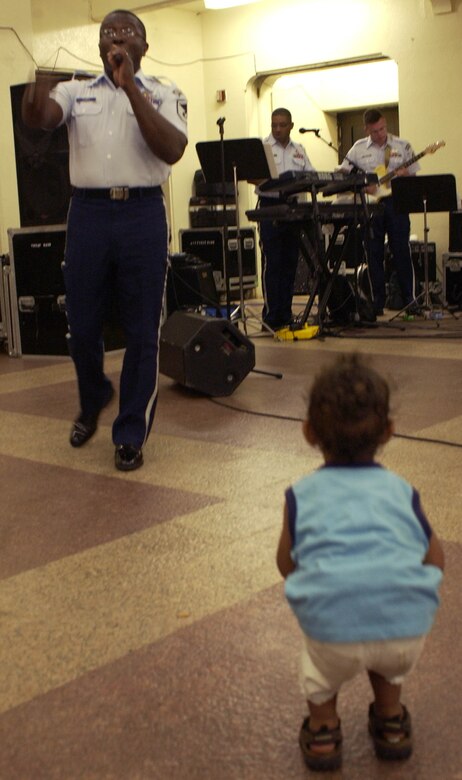 HAGATNA, Guam - A Guam youth dances as Master Sgt. John Teamer, a vocalist with the U.S. Air Force Band of the Pacific, performs along with the Alaskan Express at Chamorro Village in Hagatna, Guam.  The band visited the island in conjunction with Guam's Air Force Week.  Chamorro Village was one of many locations the band performed at from Sept. 4 to 8.  (Photo by Tech. Sgt. Brian Bahret/ 36th Wing Public Affairs)