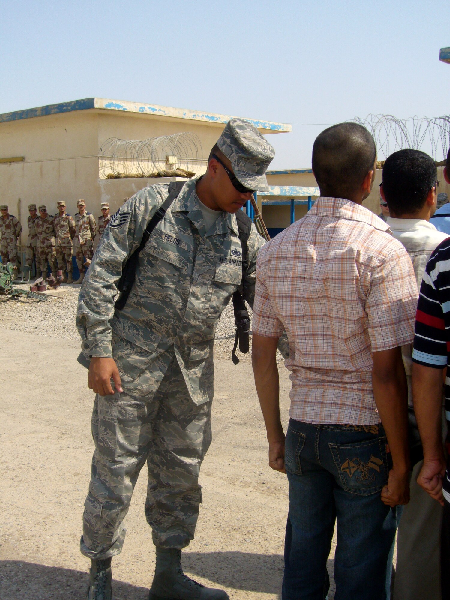 Staff Sgt. Benny Fields shows a member in the second class of Iraqi Officer Candidates how to position his hands in the position of attention while the first class of cadets look Aug. 28 at Camp Taji, Iraq. The 10 cadets will be the first to graduate from the Air Force Training Academy Sept. 12 at Taji Air Force Base, Iraq. Sergeant Fields is a member of the Coalition Air Force Transition Team, and is deployed from the 737th Training Group at Lackland Air Force Base, Texas. (U.S. Air Force photo/Maj. Edwina Walton)
