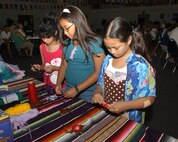 From left, Alexia Buentello, 9, Rachel Martinez, 12, and Meryl Belisario, 10, make Ojos de dios, or God's eyes, at the crafts at the the booth sponsored by the Youth Group. Alexia is the daughter of Anna Buentello, 59th Labratory Squadron. Rachel is the daughter of Staff Sgt. Dutchess Martinez, 59th Training Squadron. Meryl is  the daughter of Master Sgt. Joel Belisario, 346 Training Squadron. The girls were attending the first International Folk Festival at Lackland AFB, Texas. (USAF photo by Alan Boedeker)                              