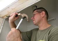 Capt. Randy Byrd trims one-quarter inch off a door frame with a hammer and chisel as he helps build a house for Habitat for Humanity of San Antonio. Captain Byrd is assigned to the 59th Medical Operations Squadron at Lackland AFB, Texas. (USAF photo by Robbin Cresswell)