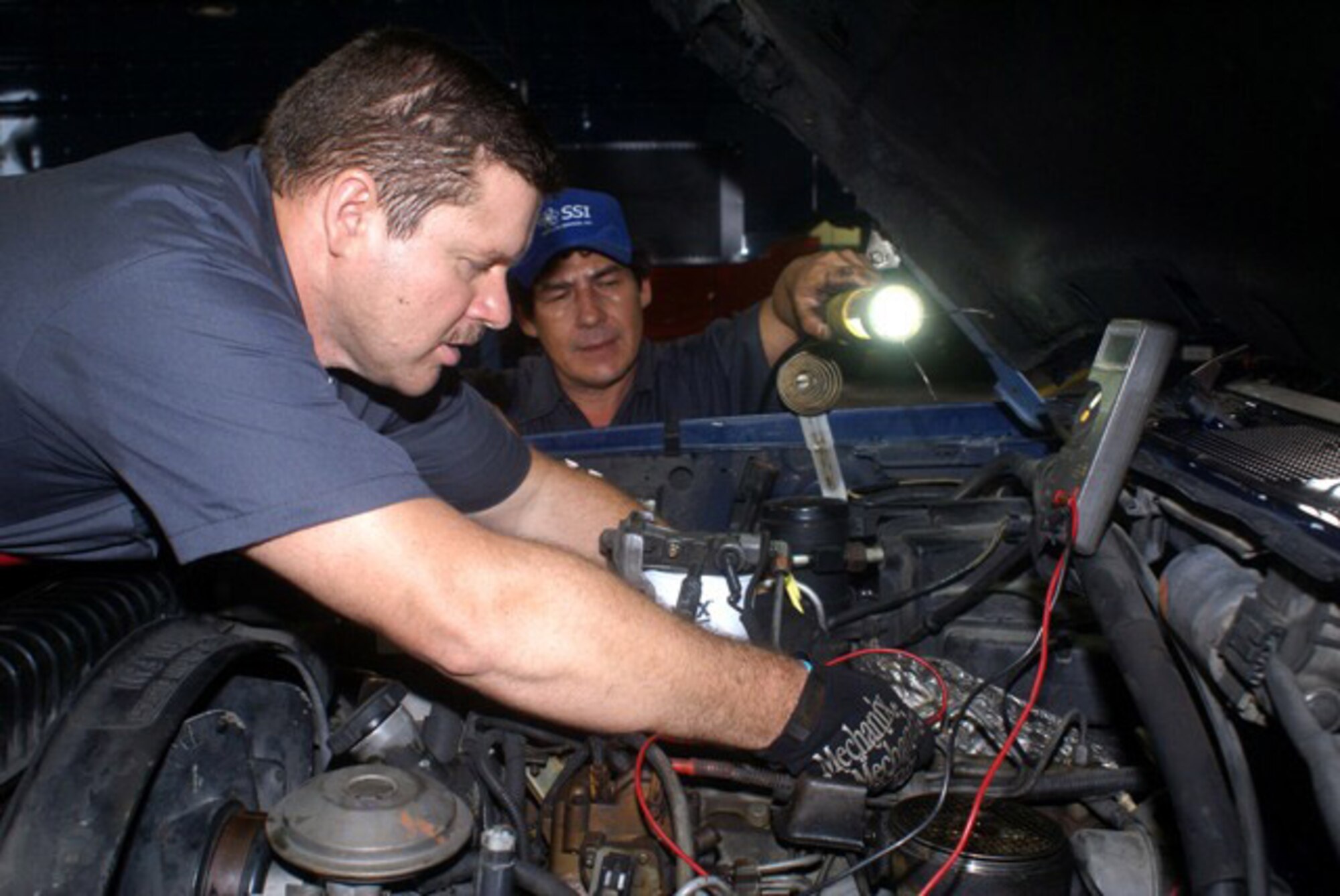 Mr. Victor Lopez (left) and Mr. Leo Valle (right), Satellite Services, Inc., automotive mechanics, perform maintenance on a Ford F-350 engine at the Homestead Air Reserve Base transportation, maintenance and operation facility. The Air Force Reserve Command recently awarded Satellite Services, Inc., a five-year contract to provide Base Operating Support Services in areas such as supply, vehicle operations and maintenance, traffic management, transient aircraft maintenance, real property maintenance, fuels management and airfield management, roads and runway maintenance and other support services. (U.S. Air Force photo/Senior Airman Erik Hofmeyer)
