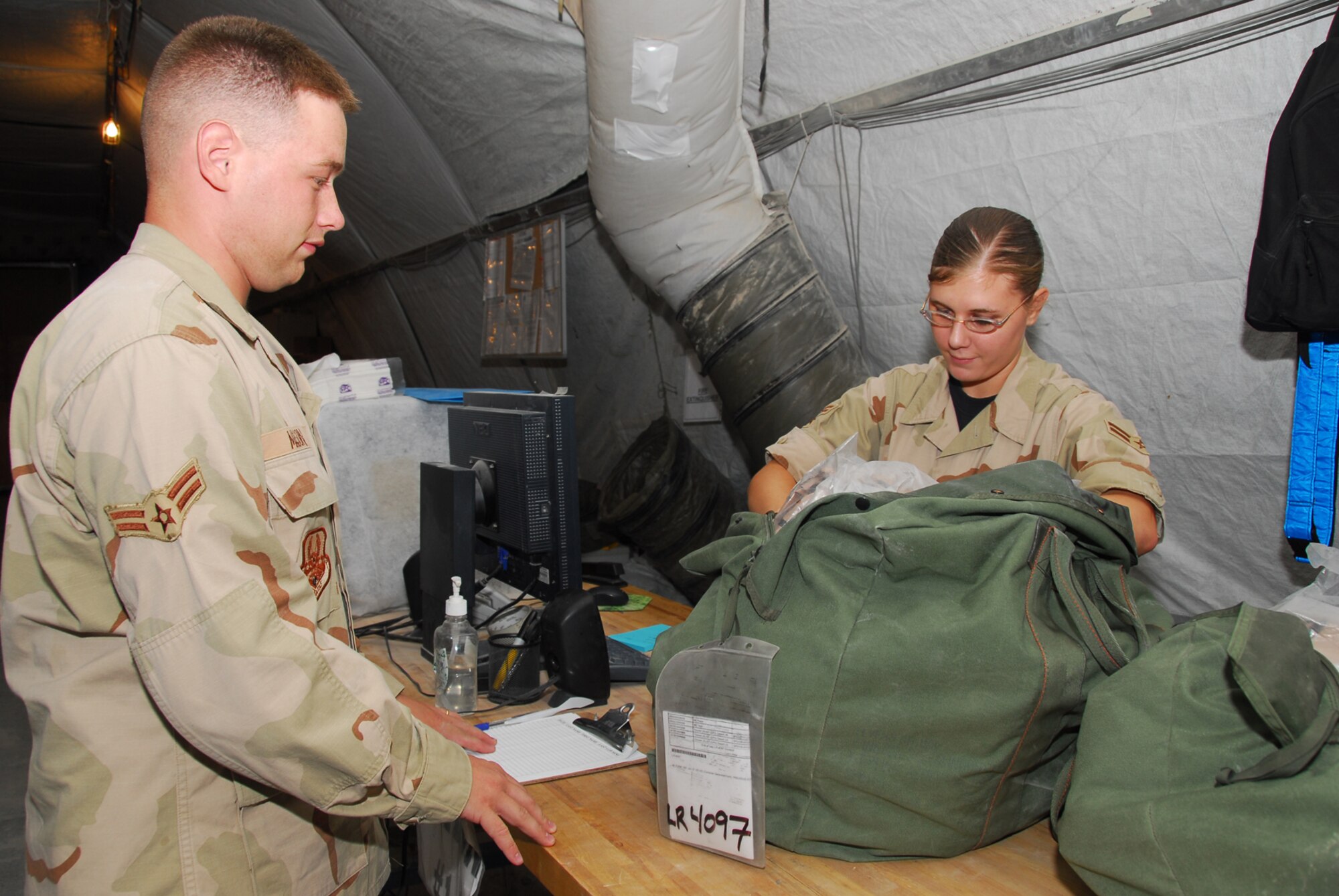 Airmen 1st Class Vanessa Fisher, and Ryan Mason, both with the 379th Expeditionary Logistics Readiness Squadron Expeditionary Theater Distribution Center, scan equipment in a C bag. The process effectively holds Airmen accountable for the equipment while they’re deployed.  (U.S. Air Force photo by Airman 1st Class Ashley Tyler)
