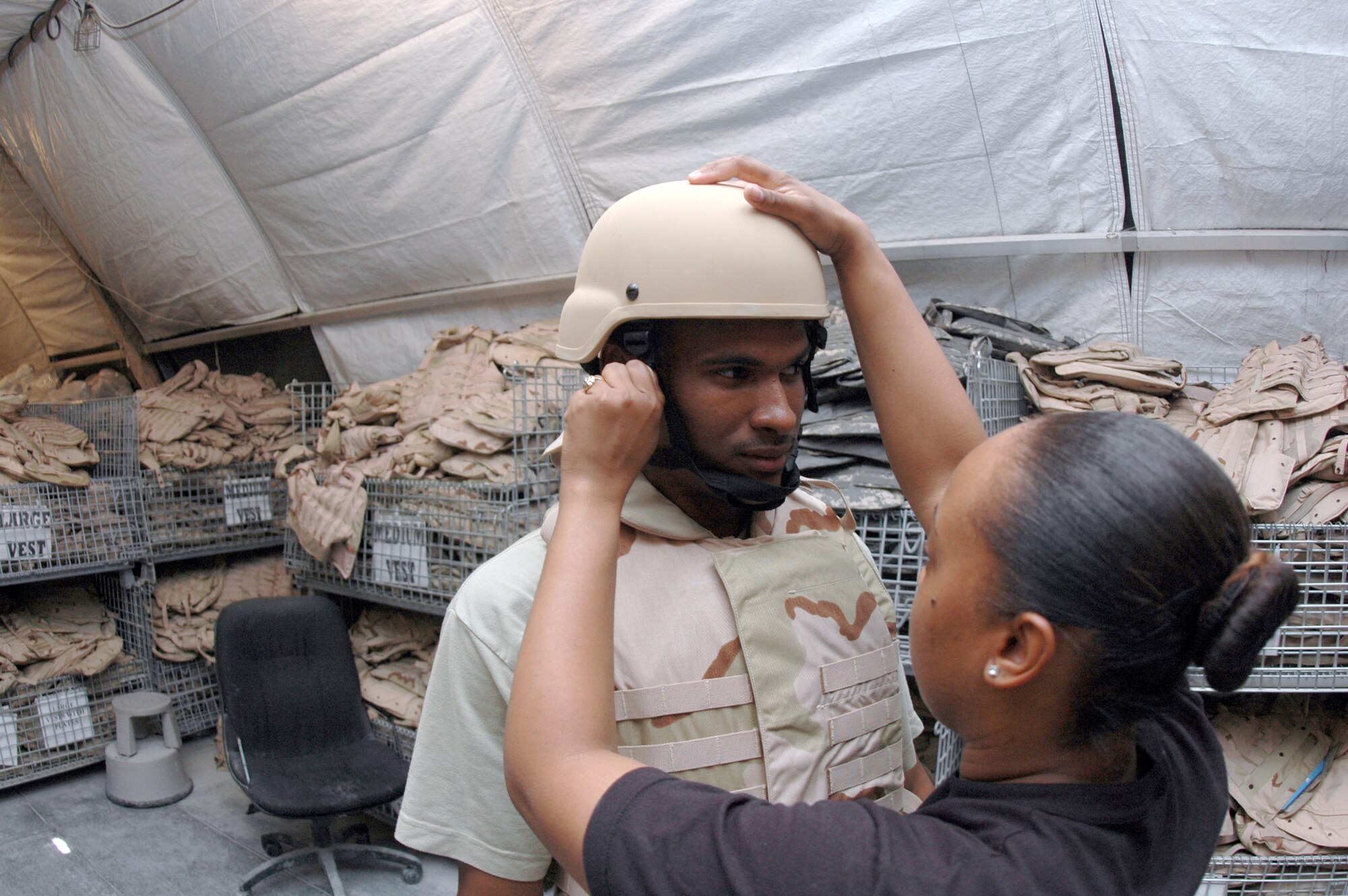 Staff Sgt. Ebonie McArthur, 379th Expeditionary Logistics Readiness Squadron Expeditionary Theater Distribution Center, fits a helmet for Airman 1st Class Terrence McIntosh. (U.S. Air Force photo by Senior Airman Clark Staehle)