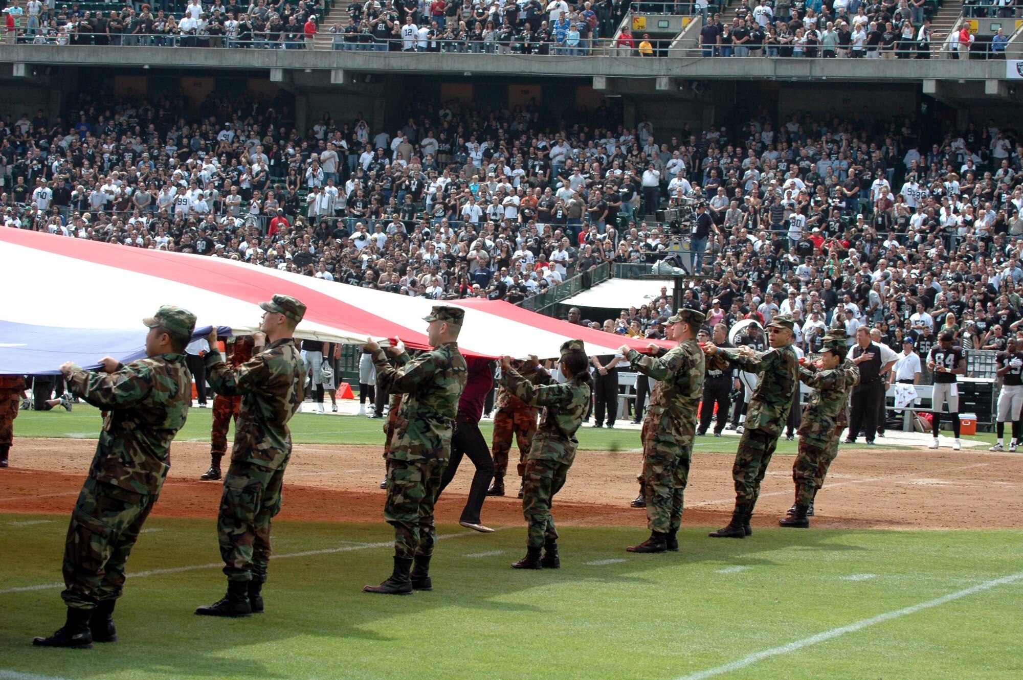 Team Travis Airmen unfurl the colors during the Oakland Raiders/Detroit Lions pre-game ceremonies at McAfee Coliseum, Oakland, Calif., Sept. 9. Travis Airmen are regularly invited to present the colors at professional sporting events in the Bay Area. (U.S. Air Force photo/Tech. Sgt. Donald Osborn)