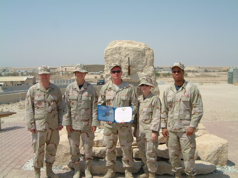 Tech. Sgt. Dale Wilson, 509th Operations Support Squadron, (center) currently assigned to the 386th Air Expeditionary Wing Expeditionary OSS, Ali Al Salem Air Base, Kuwait, displays the Navy Achievement Medal citation awarded to him Aug. 31 at a wing staff meeting. (U.S. Air Force photo printed with permission of Tech Sgt. Dale Wilson)