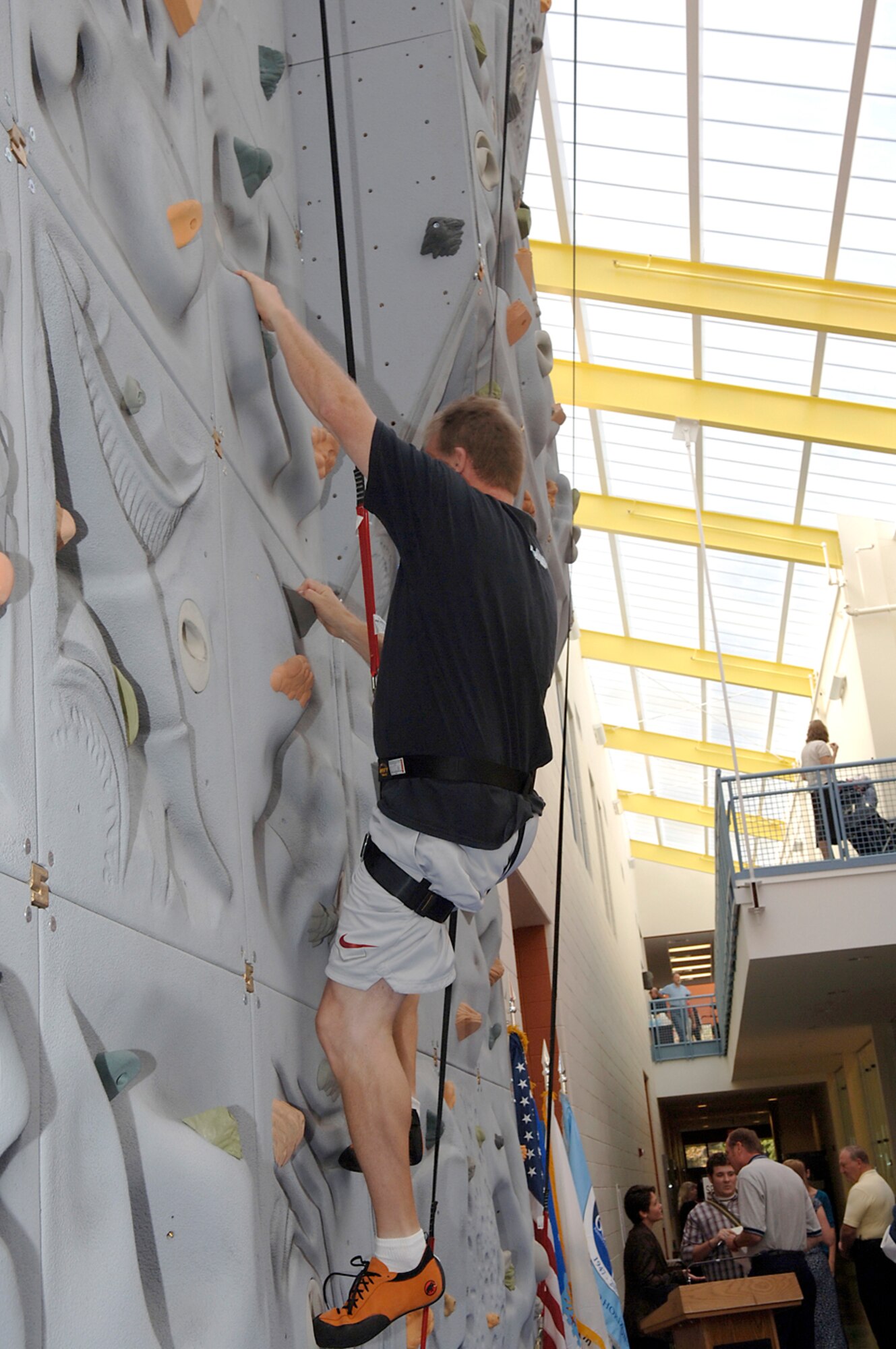 HANSCOM AFB, Mass. -- Bill Anderson, 66th Services Squadron sports director, demonstrates how to climb the rock wall following the new Fitness and Sports Center’s grand opening Sept. 5. 

The new fitness center is equipped with three racquetball courts, an indoor running track and an NCAA-sized basketball court. The facility also houses steam rooms, saunas, aerobics rooms, a family/child workout room, stretching areas, massage room,  and larger locker rooms. (Photo by Jan Abate)