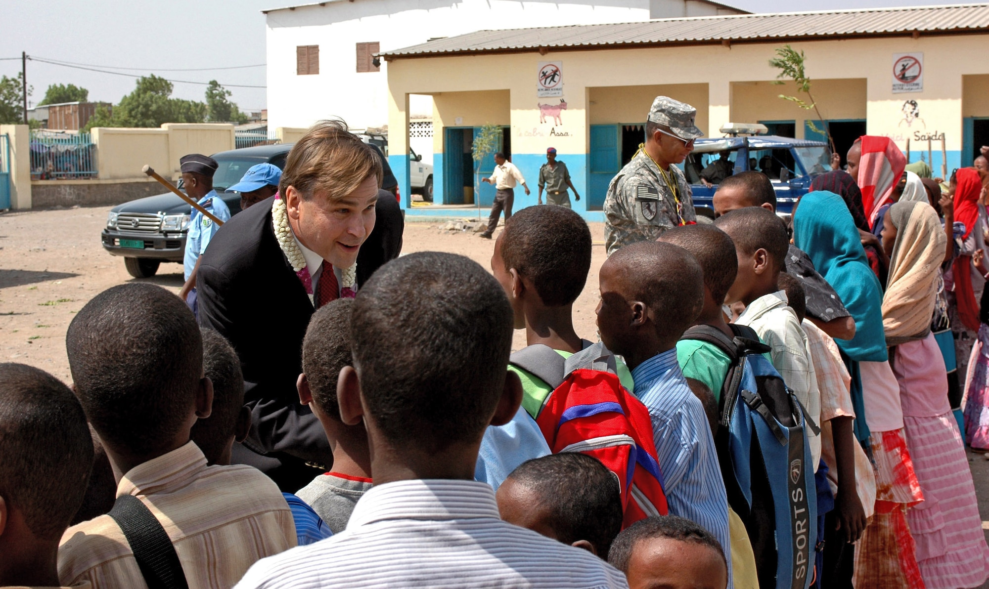 Stuart Symington and Army Brig. Gen. Sanford Holman shake hands with the students of Goubetto primary school Sept. 6 during a dedication ceremony held at the village of Balbala. The ceremony marked the hand-over of new classrooms, a stocked library, bathroom facilities, a stage area for plays and an updated power supply to the  school in the village of Balbala. Also dedicated were a kitchen and food preparation area, and a dining room for the school. Mr. Symington is the U.S. Ambassador to Djibouti and General Holman is the Combined Joint Task Force-Horn of Africa deputy commander. The project, which was handled by the Enterprise Aden Ali Company, began May 7 and finished on Aug. 7.  (U.S. Army photo/Sgt. Brandon McCarty)