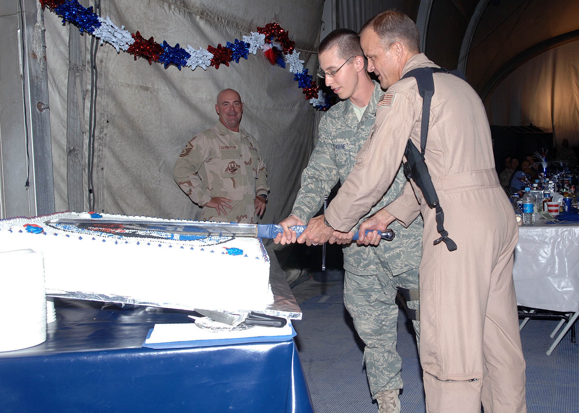 Maj. Gen. Kevin Kennedy, director of the Air Component Coordination Element, from Kabul, Afghanistan, and Airman Thomas Hawthorne, 455th Expeditionary Security Forces Squadron, ceremoniously cut the cake representing both the most senior and most junior Airman in attendance for the Air Force 60th Anniversary Ball at Bagram Airfield, Afghanistan, September 8. (U.S. Air Force photo by Staff Sgt. Craig Seals)