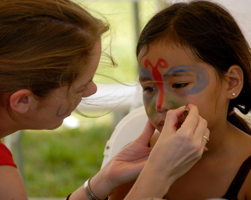 ANDERSEN AIR FORCE BASE GUAM, Airman 1st Class Kimberlee Robinson, 36th Communications Squadron, paints a girl's face at the 36 CS booster club's fund raising booth during the Air Force demonstration Sept. 8 at Ypao Beach Park. (U.S. Air Force Photo by Airman First Class Daniel Owen)