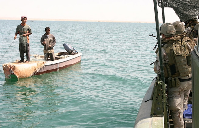 HADITHA DAM, Iraq, (Sept. 16, 2007) – Navy Petty Officer 1st Class Jesse D. Mitchell (right), a member of the Maritime Interdiction Operations Team, Detachment 3, Riverine Squadron 1, Riverine Group 1, Navy Expeditionary Combat Command, in support of Regimental Combat Team 2, warns local fishermen of the new 24-hour curfew on the Euphrates River near the dam. The regiment declared the temporary 24-hour curfew on the waterway to stem the suspected increase of enemy activity on the river during the Muslim holiday of Ramadan. Official Marine Corps Photo By Cpl. Ryan C. Heiser.