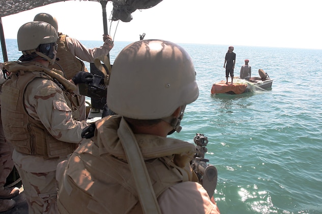 HADITHA DAM, Iraq, (Sept. 16, 2007) – Navy Petty Officer 2nd Class Lance C. Zielinski (left), a gunners mate with the Maritime Interdiction Operations Team, Detachment 3, Riverine Squadron 1, Riverine Group 1, Navy Expeditionary Combat Command, in support of Regimental Combat Team 2, and an interpreter (center) warn local fishermen of the new 24-hour curfew on the Euphrates River near the dam. The regiment declared the temporary 24-hour curfew on the waterway to stem the suspected increase of enemy activity on the river during the Muslim holiday of Ramadan. Official Marine Corps Photo By Cpl. Ryan C. Heiser.