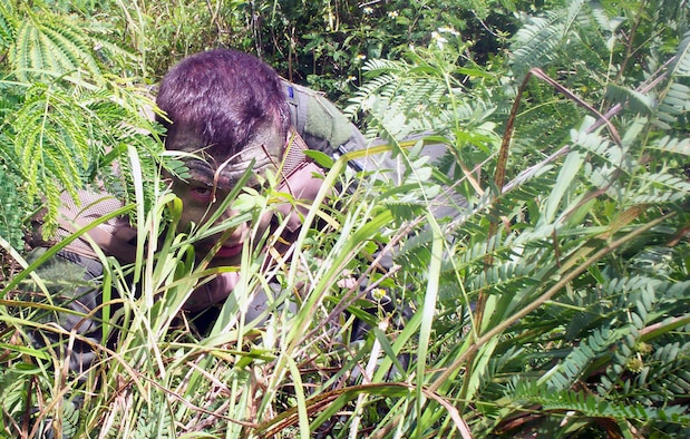 Lt. Adam Jones, 20th Expeditionary Bomb Squadron, plays the role of a surviving aircrew member in the jungle terrain of Guam. Lieutenant Jones practiced his evasion techniques and attempted to elude enemy forces until his rescue coordinated in a joint effort by Air Force personnel and their Navy counterparts.