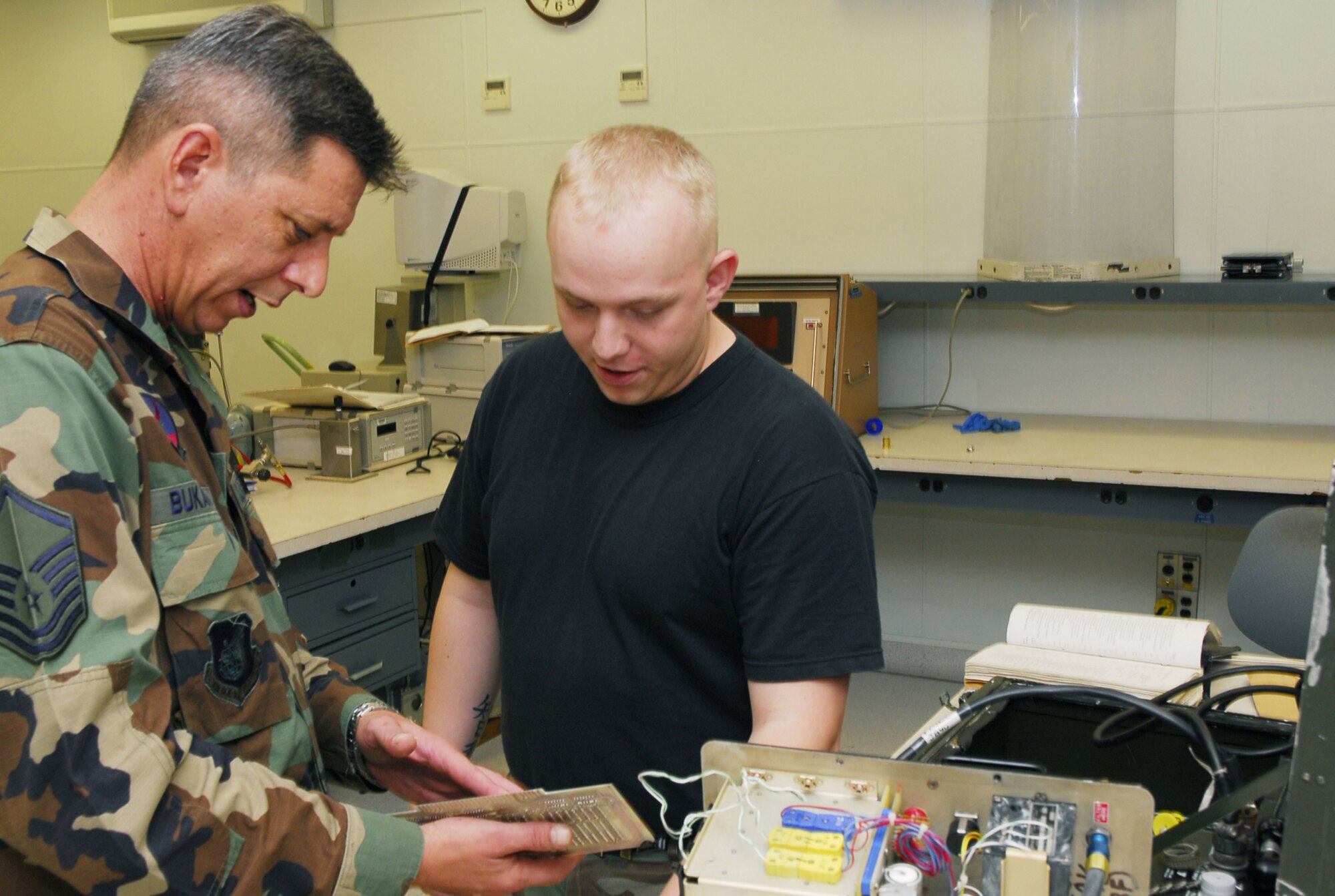 Master Sgt. Robert Bukantas (left) inspects a jet engine analyzer while Senior Airman Andrew Utter looks on at Kadena Air Base, Japan, Sept. 11, 2007. The precision measurement equipment laboratory performs and manages repair, calibration, and modification of test, measurement, and diagnostic equipment standards and automatic test equipment. Both Airmen are assigned to the 18th Component Maintenance Squadron. (U.S. Air Force photo/Airman 1st Class Sheila deVera)
