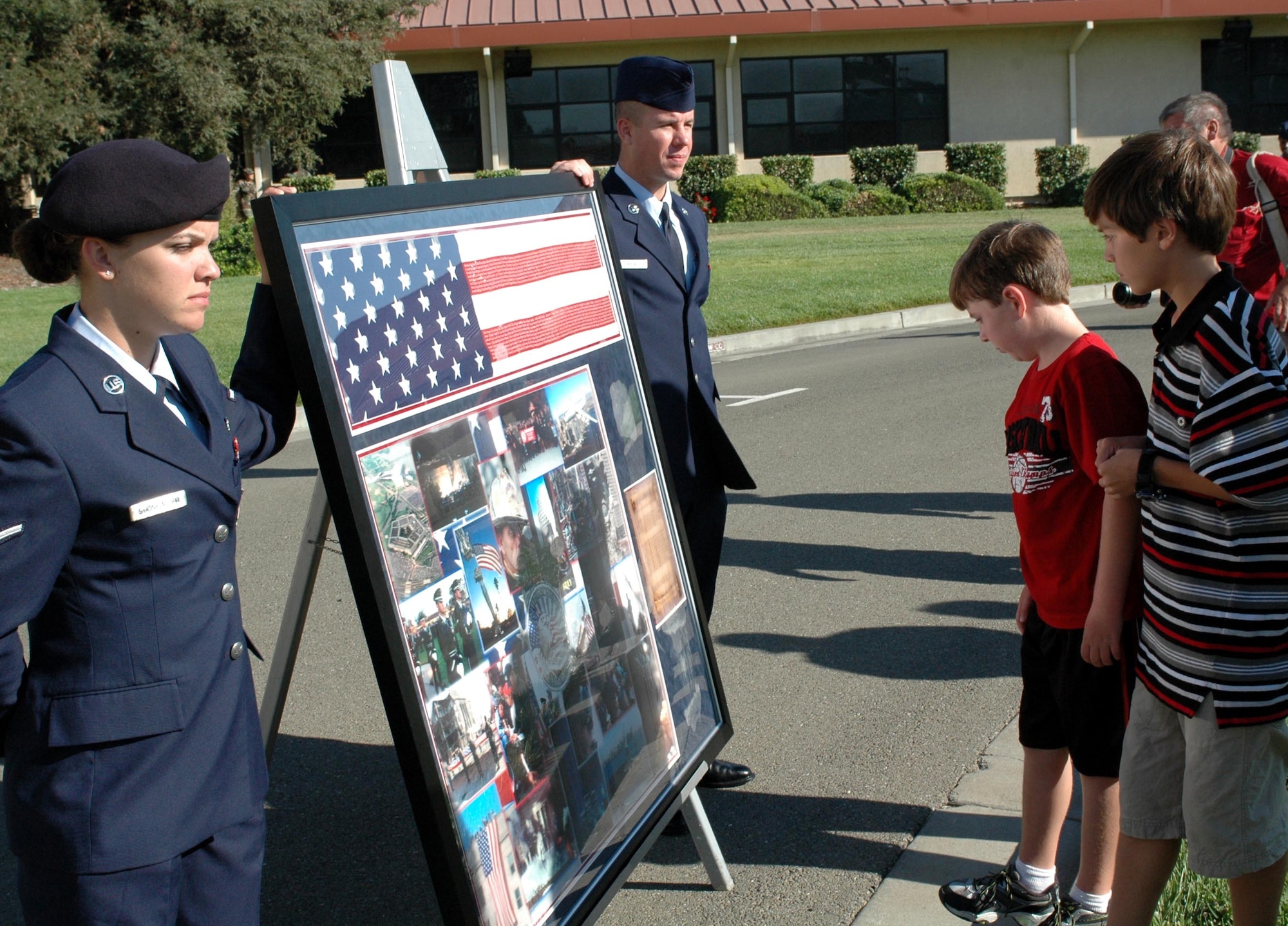 Stevie Arquiette, (second from right), son of Col. Steve Arquiette, 60th Air Mobility Wing commander, and Nicholas Tuck, son of Col. G. I. Tuck, 60th Air Mobility Wing vice commander, view the Sept. 11, 2001 memorial plaque. The plaque holds a memorial flag which list all the names of the individuals who lost their lives on Sept. 11, 2001. (U.S. Air Force photo/Staff Sgt. Candy Knight)