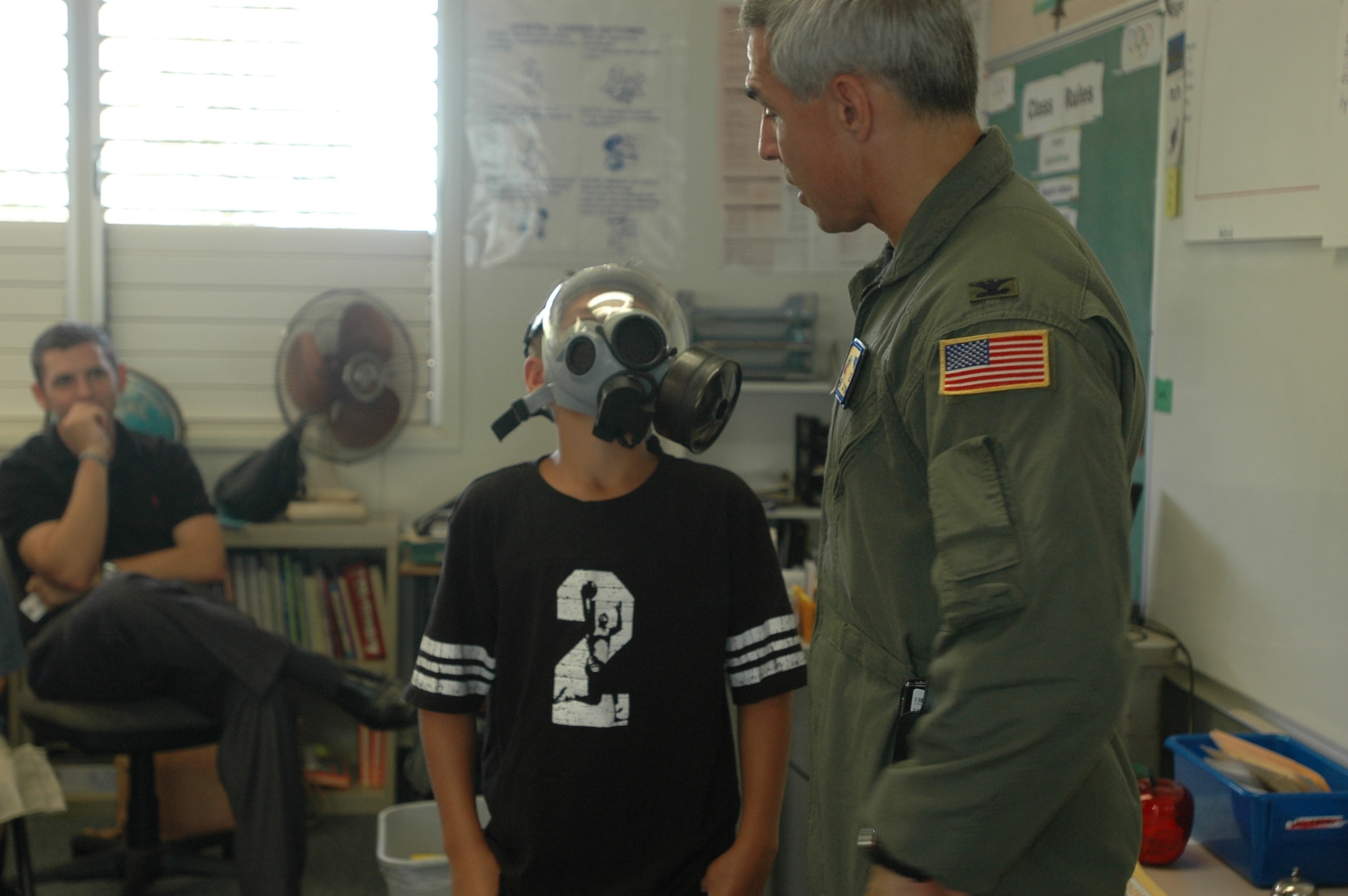 Col. J.J. Torres, 15th Airlift Wing commander, shows a student at Hale Kula Elementary School, Schofield Army Barracks, Hawaii some of the gear Airmen wear during Airmen in Education Day. Air Force members visited island schools during Airmen in Education Day, part of the Air Force Week Honolulu celebration. Photo by 2nd Lt. Melanie McLean.