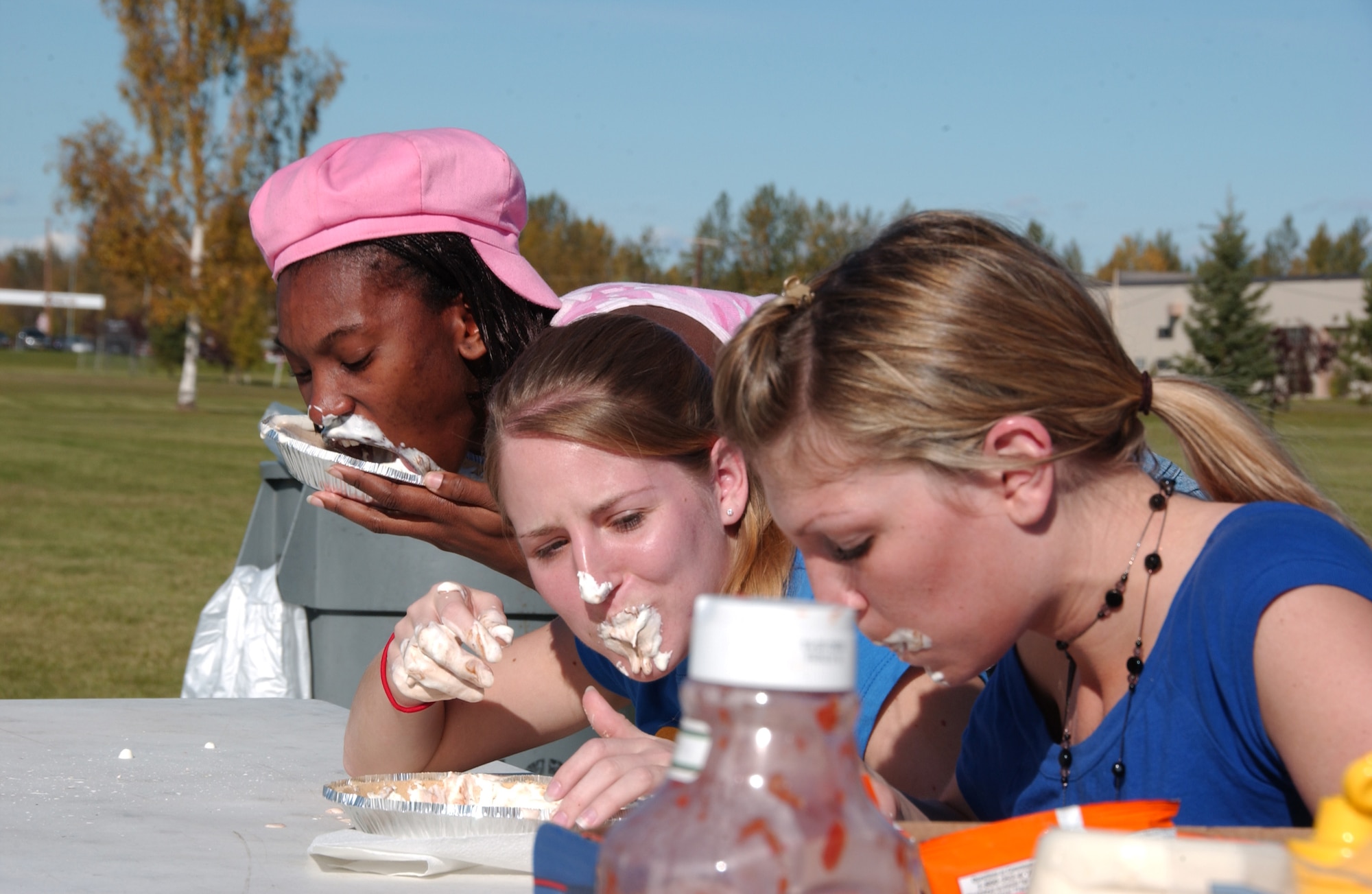 EIELSON AIR FORCE BASE, Alaska -- Airman 1st Class Apryl Modeste (back), 354th Security Forces Squadron, Airman 1st Class Krystal Bernowski (middle), 354th Logistics Readiness Squadron, Senior Airman Amy Cosillos (front), 354th Operations Group, compete in a pie eating contest Sept. 7 inbetween the dormitories. The  Airman block party was hosted by Airman Committed to Excellence in efforts to raise morale on base before the long winter. (U.S. Air Force Photo by Airman 1st Class Jonathan Snyder) 