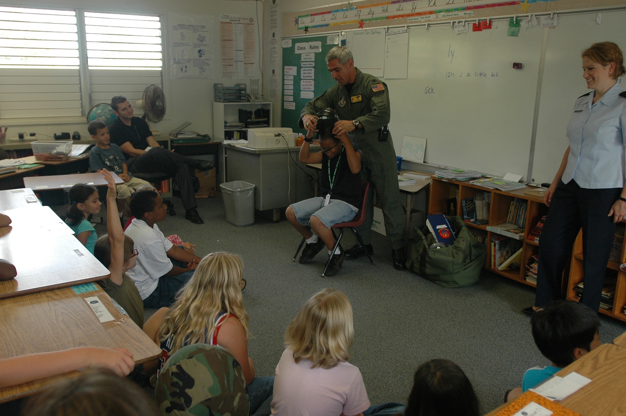 Col. J.J. Torres, 15th Airlift Wing commander, shows a student at Hale Kula Elementary School, Schofield Army Barracks, Hawaii  the gear necessary to be a pilot during Airmen in Education Day. Air Force members visited island schools during Airmen in Education Day, part of the Air Force Week Honolu celebration. Photo by 2nd Lt. Melanie McLean.