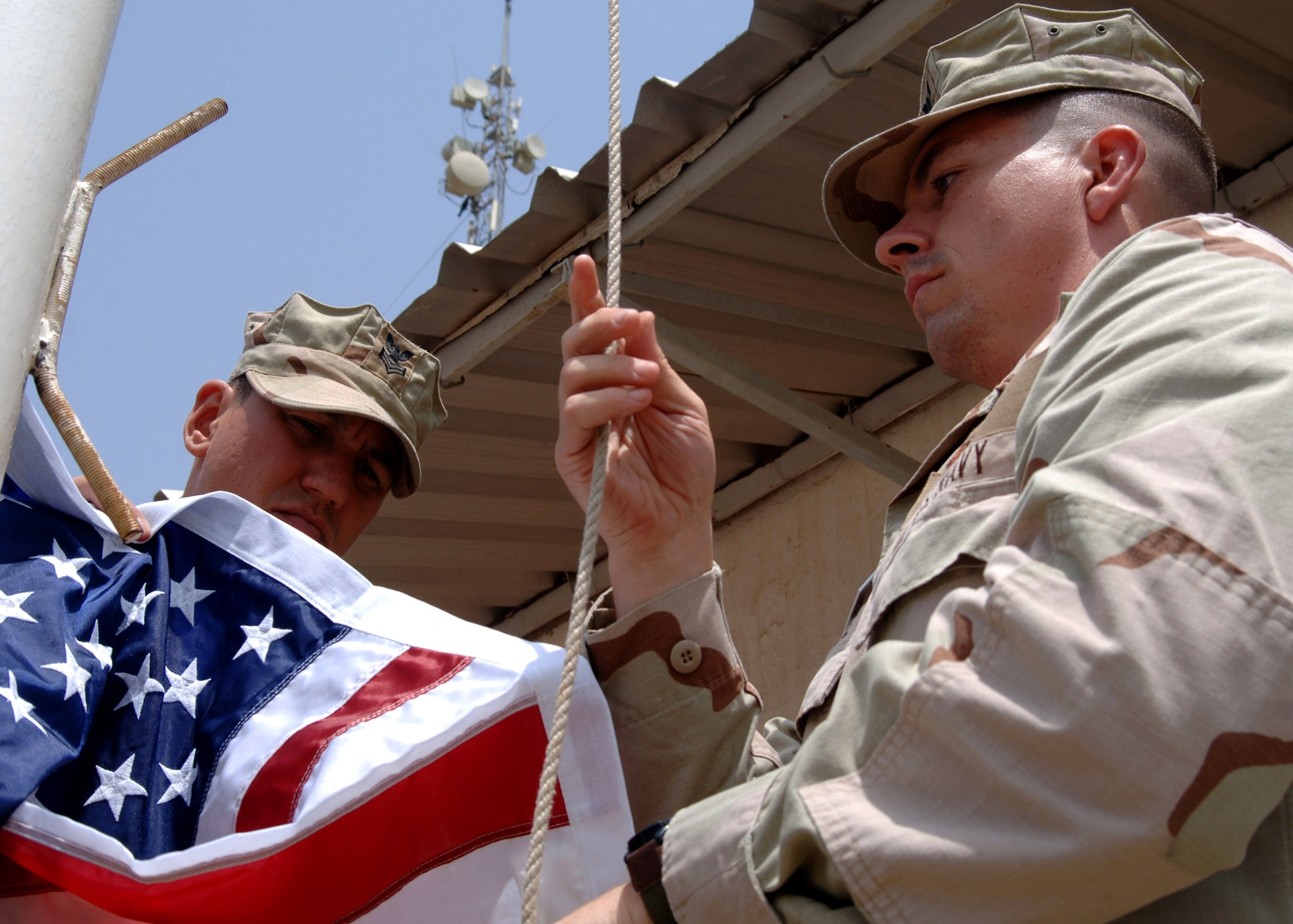Navy Petty Officer 1st Class David Trimble and Navy Petty Officer 1st Class Wayne George raise a flag Sept. 11 over Camp Lemonier, Djibouti. The flag was purchased by servicemembers deployed to Combined Joint Task Force-Horn of Africa in remembrance of Sept. 11, 2001. (U.S. Navy photo/Petty Officer 2nd Class Regina L. Brown)
