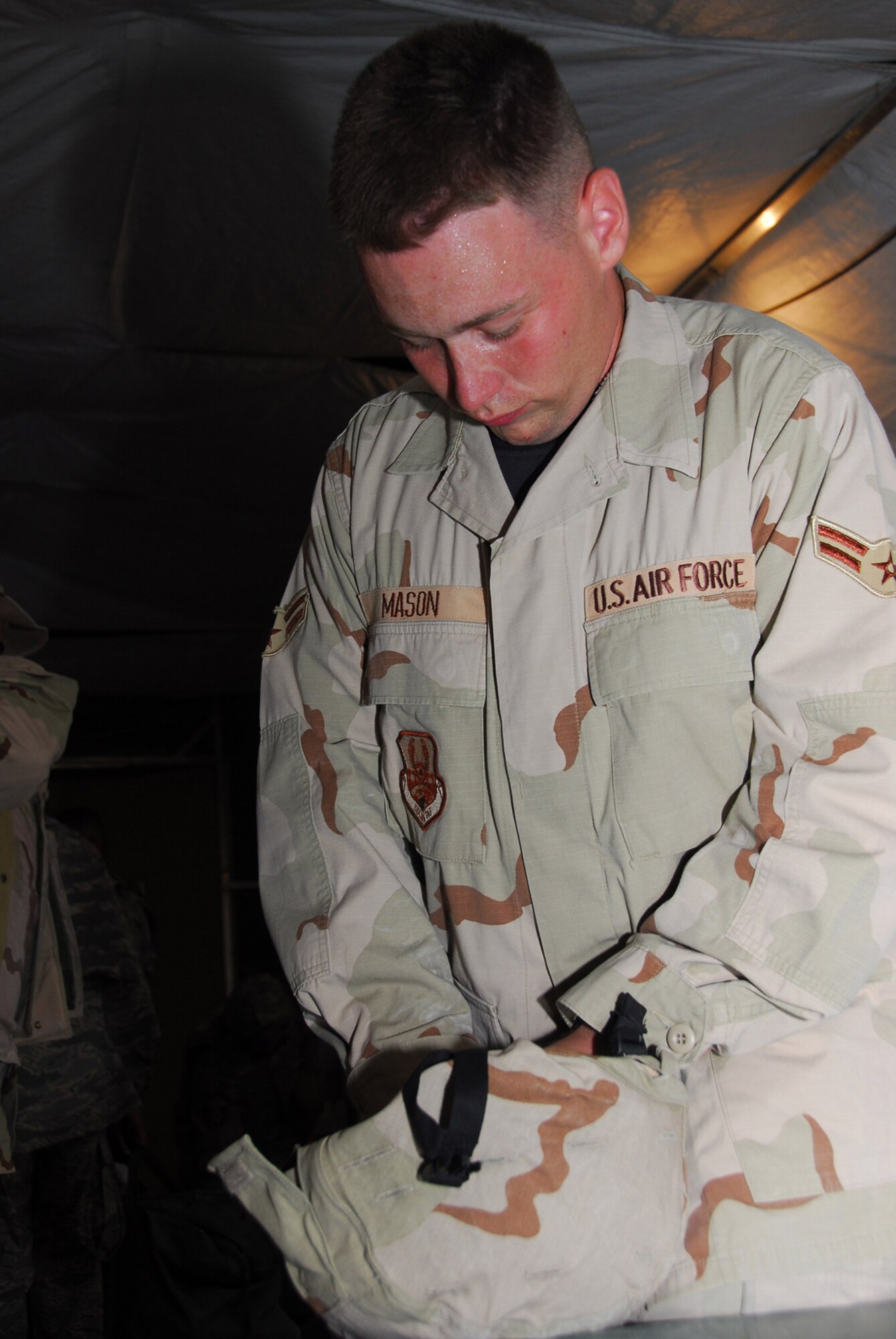 Airman 1st Class Ryan Mason attaches a desert camouflage cover to a helmet Sept. 1 in Southwest Asia. Airman Mason is deployed to the 379th Expeditionary Logistics Readiness Squadron Expeditionary Theater Distribution Center. (U.S. Air Force photo/Airman 1st Class Ashley Tyler)