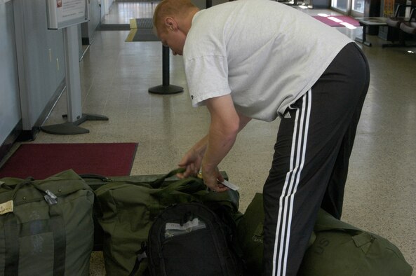 Capt. Drew Downey, 320th Missile Squadron, ties identification tags to his luggage at the Cheyenne Regional Airport Aug. 23. Captain Downey is deploying to Southeast Asia (Photo by 2nd Lt. Lisa Meiman).