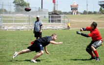Airman 1st Class Ryan Hendrick, 321st Missile Squadron, dashes toward quarterback Staff Sgt. Pedro Cantu, 90th Security Forces Squadron. The game between the two teams went into triple overtime with the black team, the ‘Dirty Dozen,’ winning against the red team, the ‘C-FLT Gamecocks,’ 42 to 34.