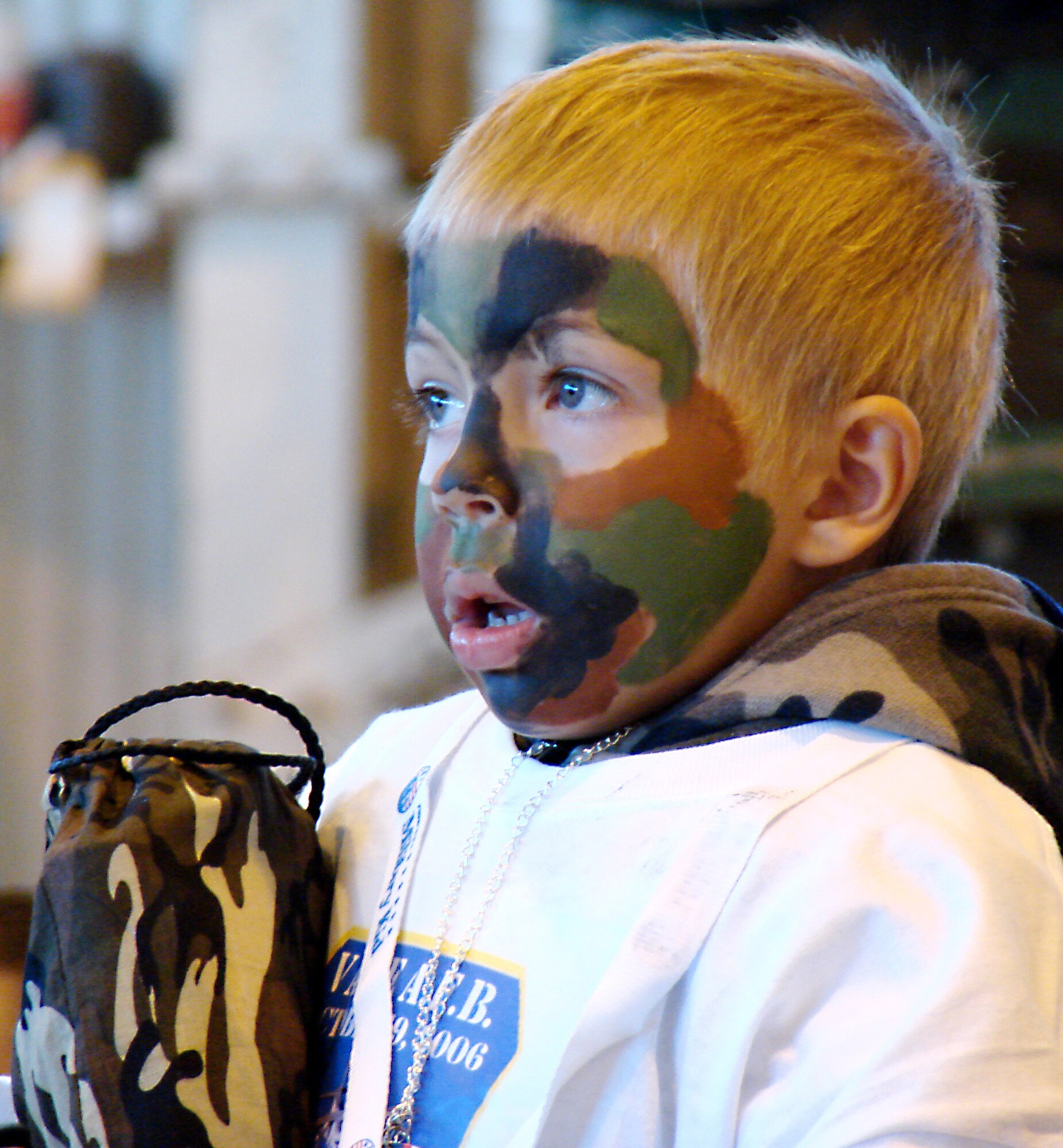 Noah Estes, son of Mary and Tech. Sgt. Ken Estes, 71st Medical Group, waits to report to his next processing station after getting camouflaged by members of the 71st Security Forces Squadron during Operation KIDS 2006. Sergeant Estes said Noah had a great time last year and is looking forward to "redeploying" this year. (US Air Force photo by 2nd Lt. James Justice)                 