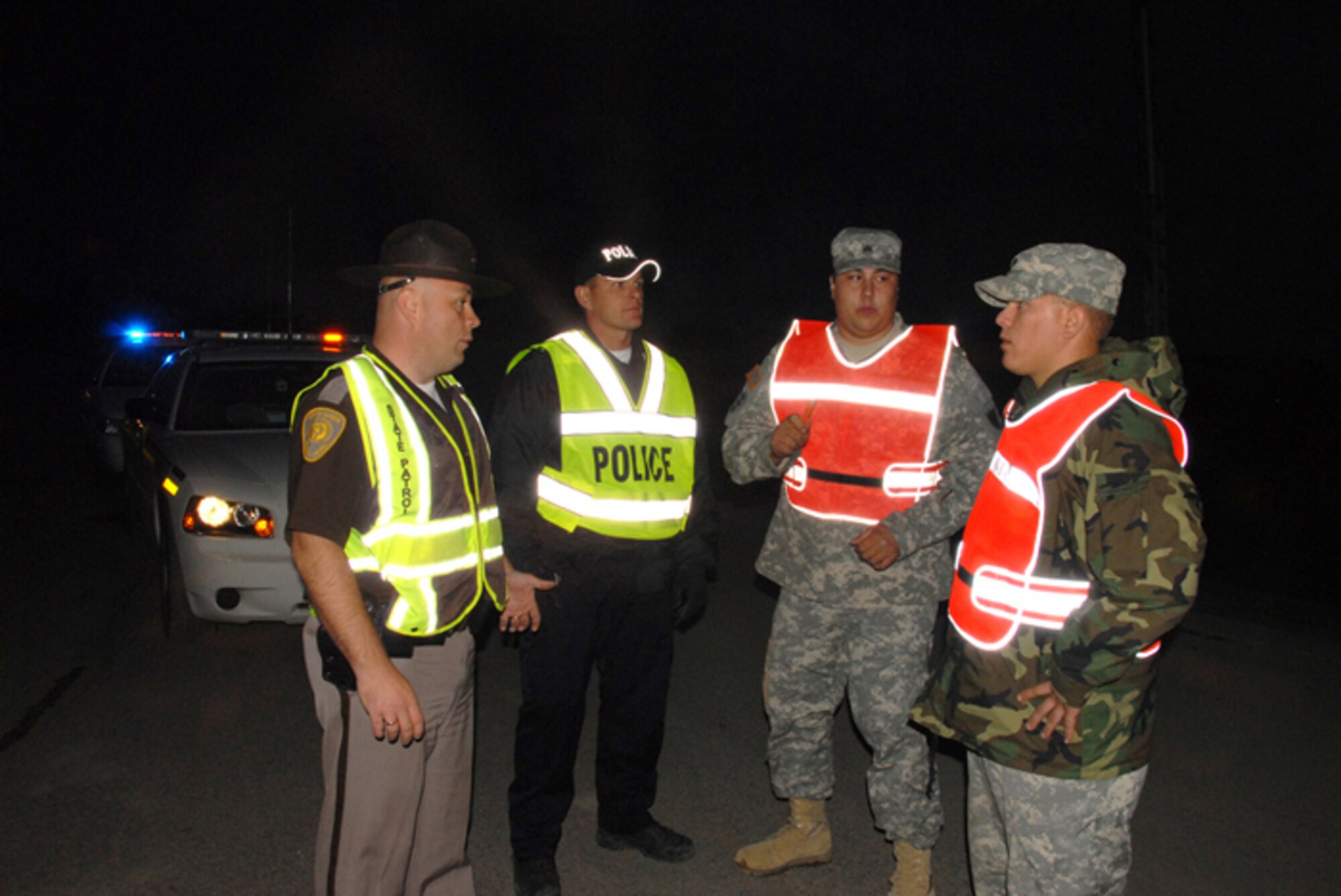 From right to left, Specialist Shane A. Korynta and Sergeant Danny J. Lemieux Jr., both of the 188th Engineer Company, assume security responsibilities at an entry control post on the outskirts of Northwood, N.D., from law enforcement officials Jeremy Hanson, Larimore, N.D., police chief, and N.D. Highway Patrol trooper Aaron Enzminger.  Entry to the town of Northwood was completely closed and secured by the North Dakota National Guard from 8 p.m. until 8 a.m. during the nights following an F4 tornado that hit Northwood, N.D., Sunday, Aug. 26. (USAF photo/Senior Master Sgt. David H. Lipp)
