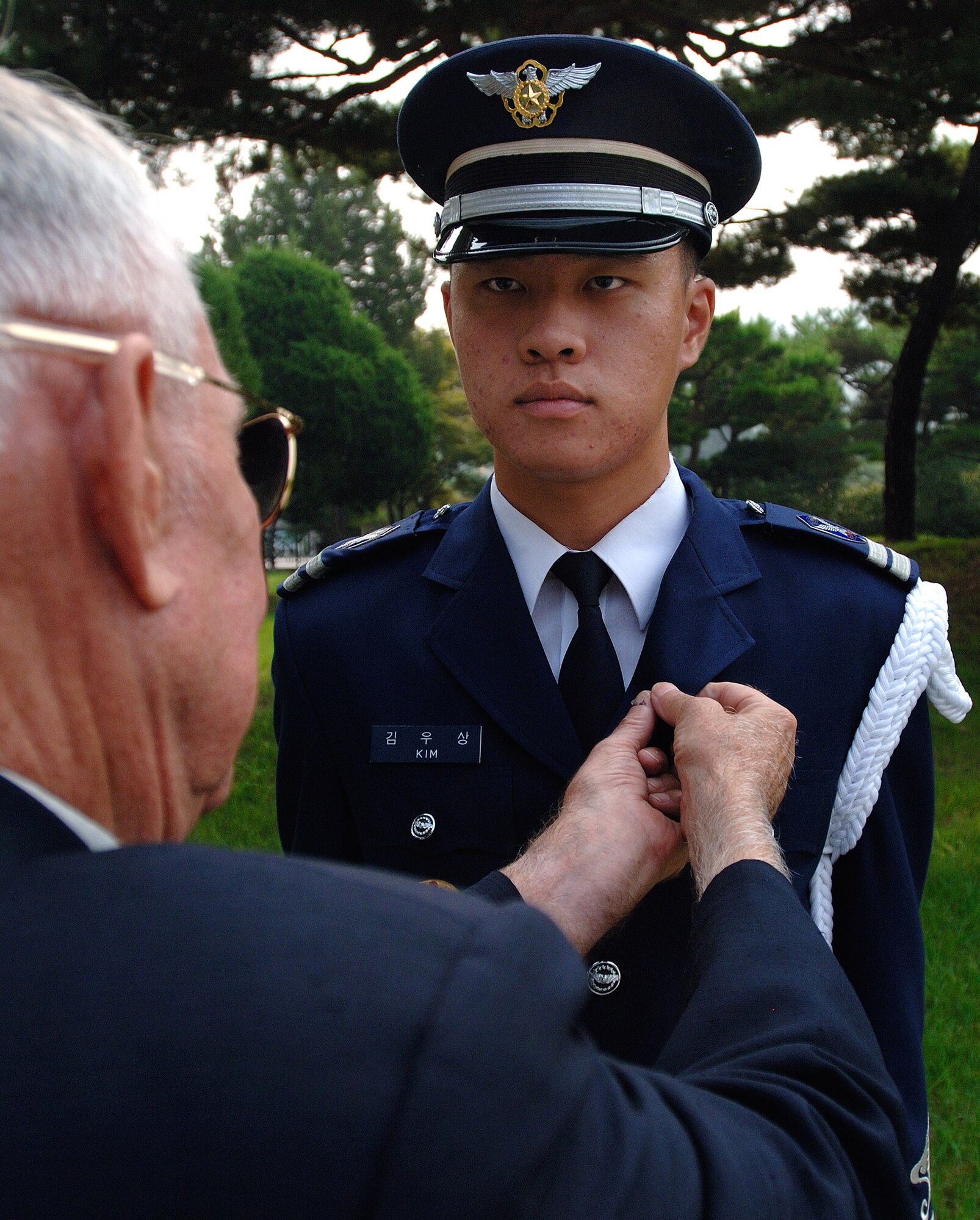 Retired Col. Harold Fischer places an F-86 Sabre pin to the lapel of a South Korean National Honor Guard member Woo-Sang Kim after a wreath-laying ceremony at the South Korean National Cemetery Sept 12. Colonel Fischer is a Korean War double ace with 10 confirmed MiG kills. The South Korean government's Revisit Korea program invites war veterans each year to come to South Korea to honor the men and women from 21 countries who served during the Korean War. Nearly 25,000 veterans have participated in this program since 1975. (U.S. Air Force photo/Staff Sgt. Bennie J. Davis III) 
