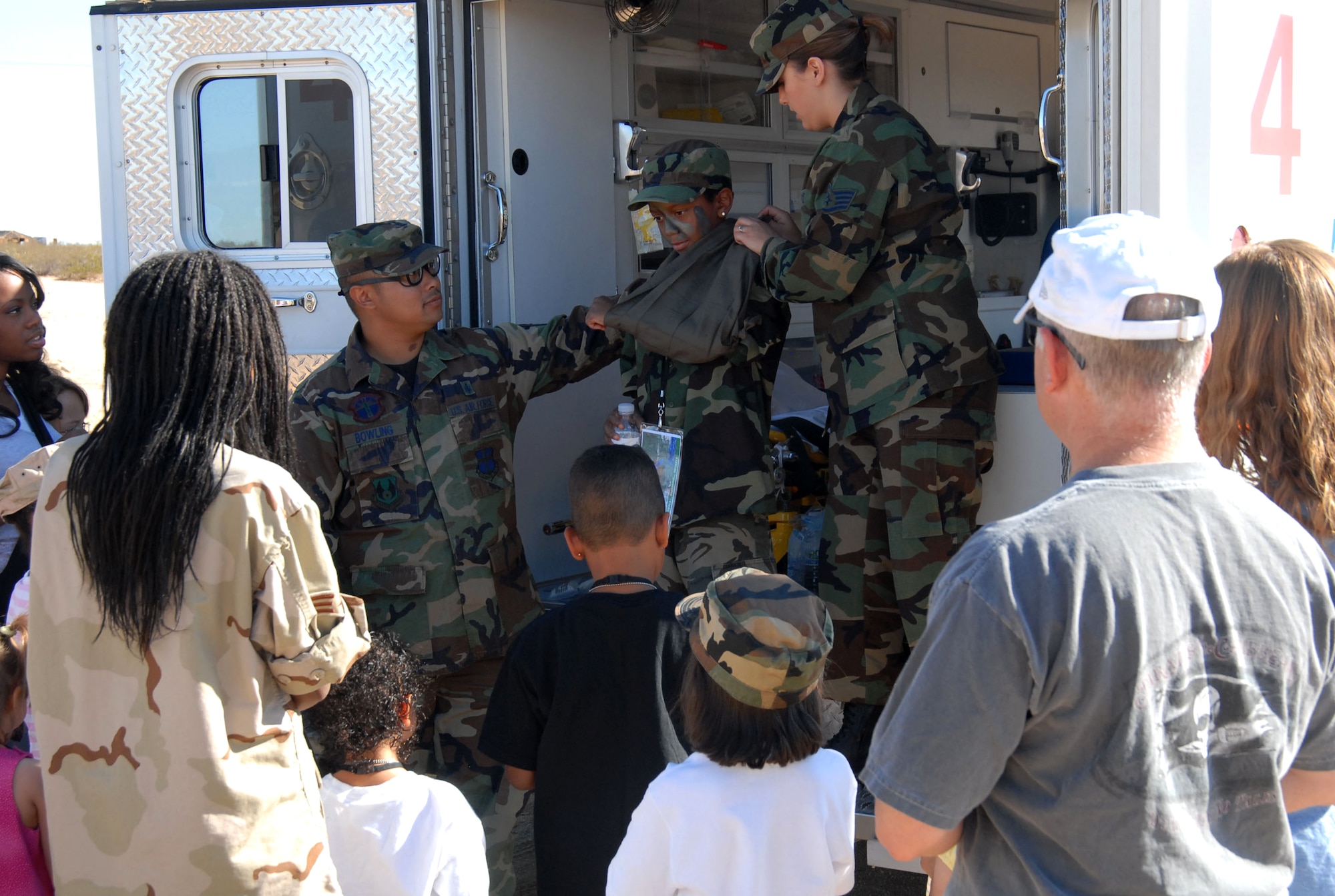 Christopher Monget, age 10, volunteers to play injured as Tech. Sgt. Jahnpayne Bowling, 95th Aerospace Medicine Squadron medical technician, and Staff Sgt. Lindsey Wilkinson, 95th Medical Operations Squadron medical technician, demonstrate self aid and buddy care to the "deployed" youth. The youth are deployed as part of the "Kids Understanding Deployment Operations" program. Operation KUDOS is designed to inform youth about life in a deployed environment.  (Photo by Airman 1st Class Mike Young)