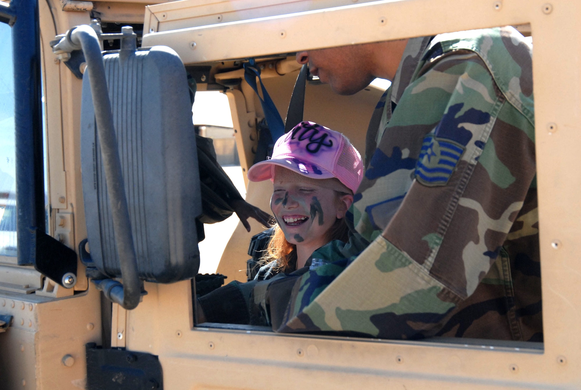 Caitlin Lane, 12, sits behind the wheel of a Humvee during “Operation KUDOS” Saturday. Operation KUDOS is a program designed to give children a first-hand look at what their parents go through while deployed. (Photo by Airman 1st Class Mike Young)