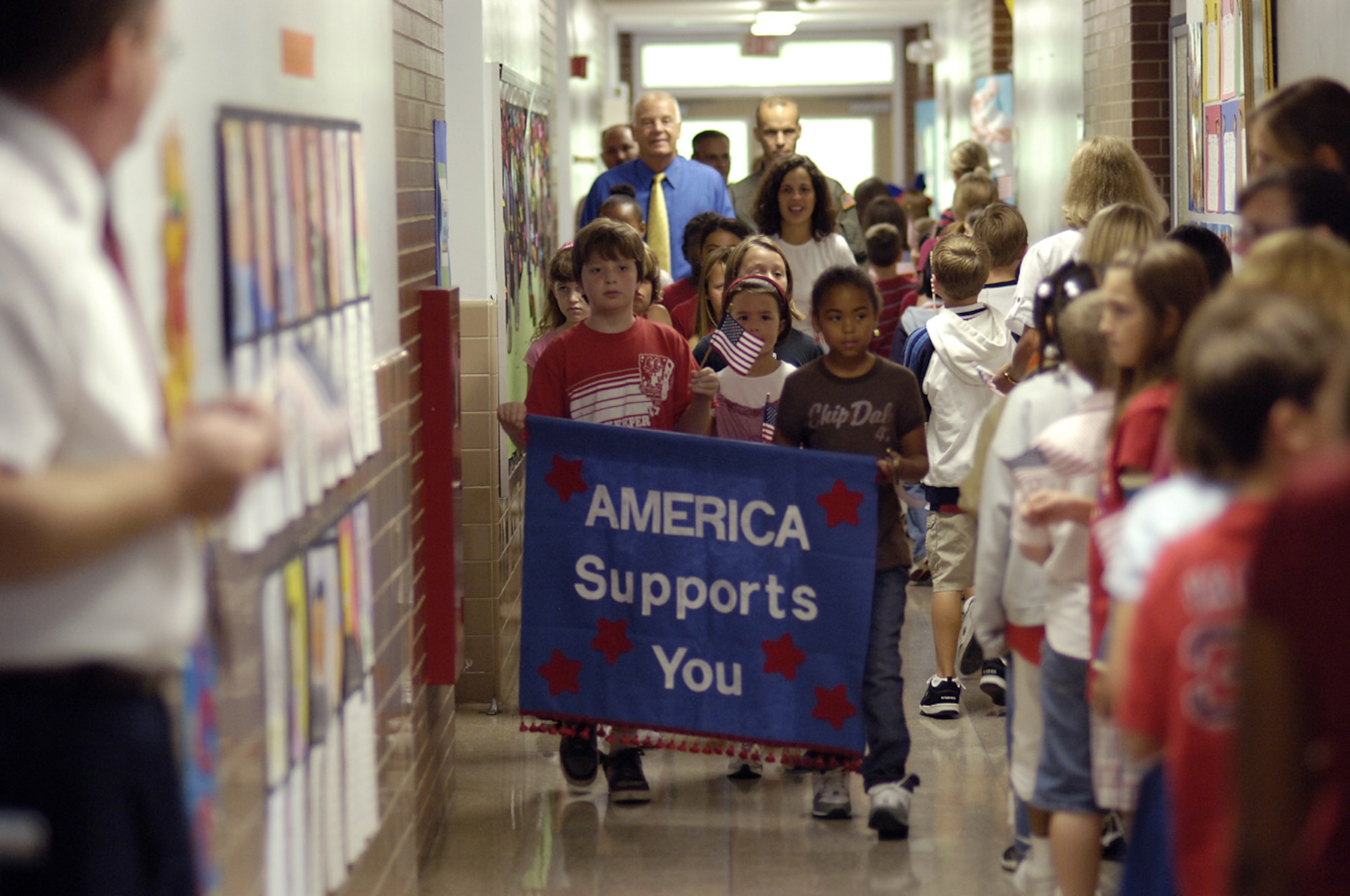 John Humphries, a fourth grader, and Adrenna Steinert, a third grader, both students at the Columbia School, McGuire Air Force Base, NJ, carry a banner in a march to commemorate the 6th anniversary of the 9/11 terrorist attacks. The two students led the America Supports You Freedom Walk, which included Dr. Richard Carson, superintendent of the North Hanover school district and Col. Bill Spacy, 305th Air Mobility Wing vice commander, through the hallways to show their support for the troops at McGuire AFB. Dependents of military families make up the majority of the school district’s students.  (USAF photo by Kenn Mann.)