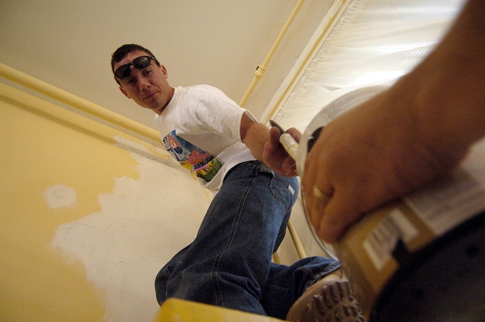 2nd Lt. Jeffery Smart, 1st Combat Camera Squadron, dips his paint brush into a paint can held by Tech. Sgt. Michael Hasenauer, 1 CTCS, while painting the common area of the Florence Crittendon house in downtown Charleston Tuesday for lower income, single and at-risk pregnant women. (U.S. Air Force Photo/Tech. Sgt. Jeremy Lock)          