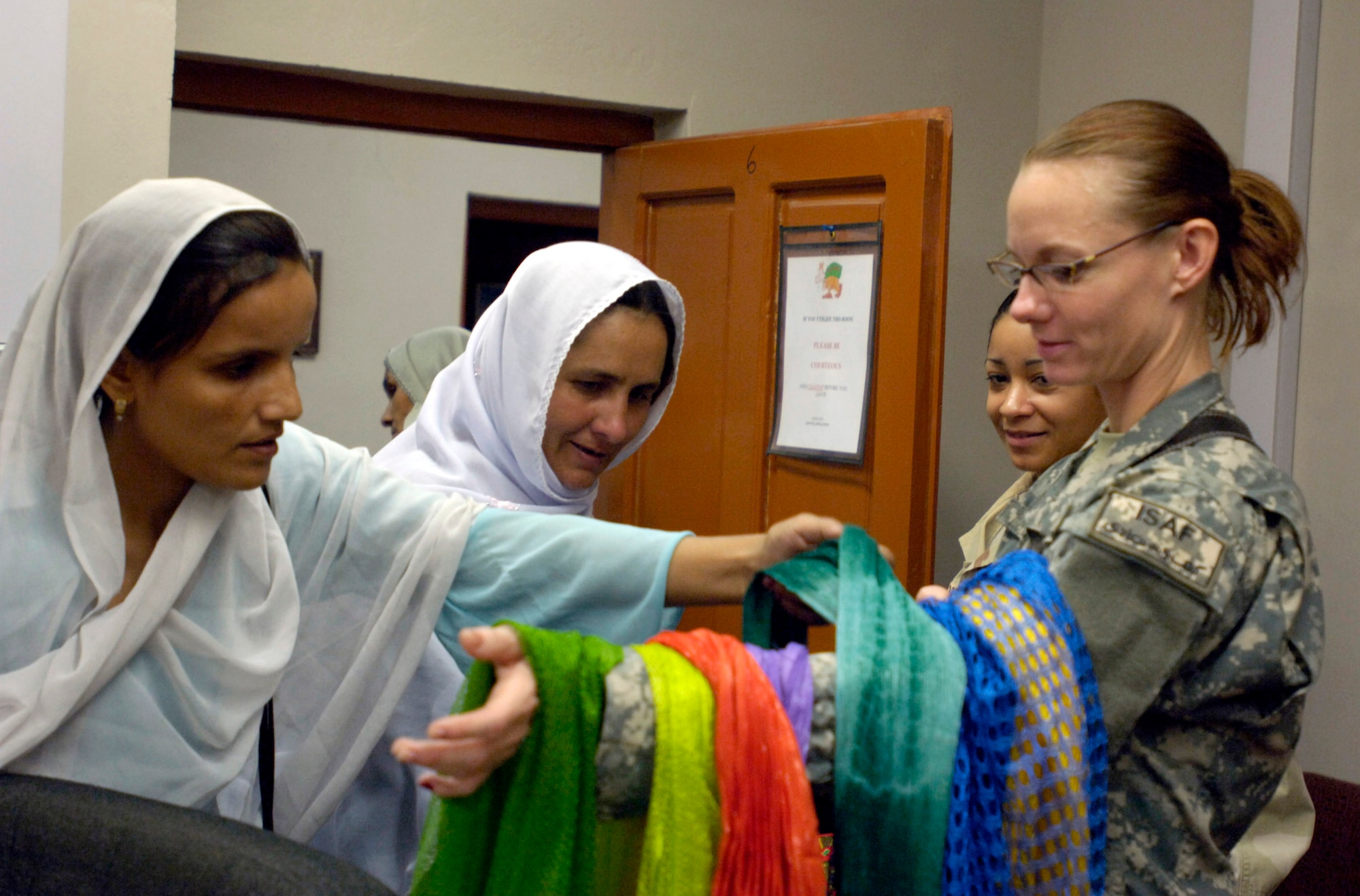 Capt. Heather Kekic offers shawls as gifts to Afghan women who attended a tea Sept. 5 at Forward Operating Base Mehtar Lam, Afghanistan. Female Airmen and Soldiers assigned to the Laghman Provincial Reconstruction Team hosted the tea for influential Afghan women living throughout Afghanistan's Laghman province. Captain Kekic, who is the PRT's public affairs and information officer, is deployed from Randolph Air Force Base, Texas. (U.S. Air Force photo/Staff Sgt. Julie Weckerlein)