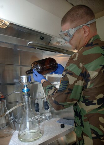 Tech. Sgt. Joseph Maurin, NCO in charge of 437th fuels laboratory, demonstrates the bottle method to check for particulates in the sediment inside of a fume hood at the lab on base Monday. (U.S. Air Force photo/Airman 1st Class Cynthia Spalding)